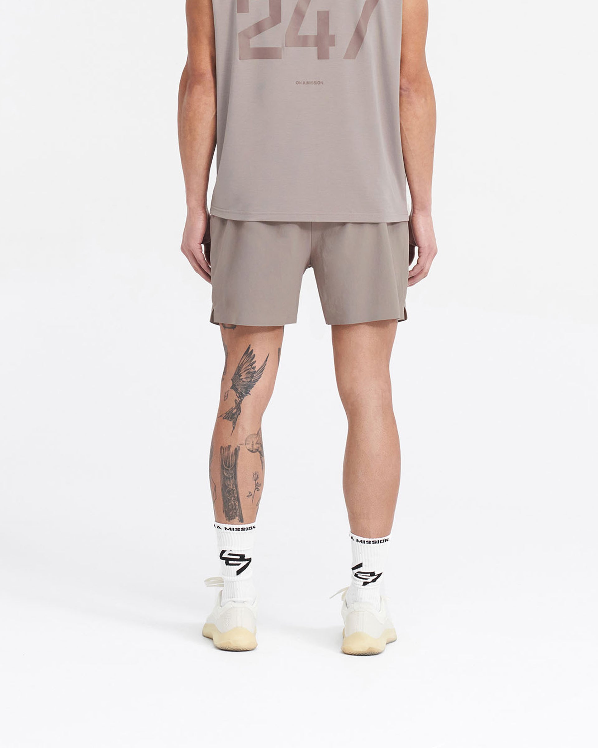 Man wearing grey gym shorts on a plain white background | 247 Fused Shorts in Cinder | Gym shorts with 247 branded waistband and quick-dry fabric | 247 Shorts | Represent Clo