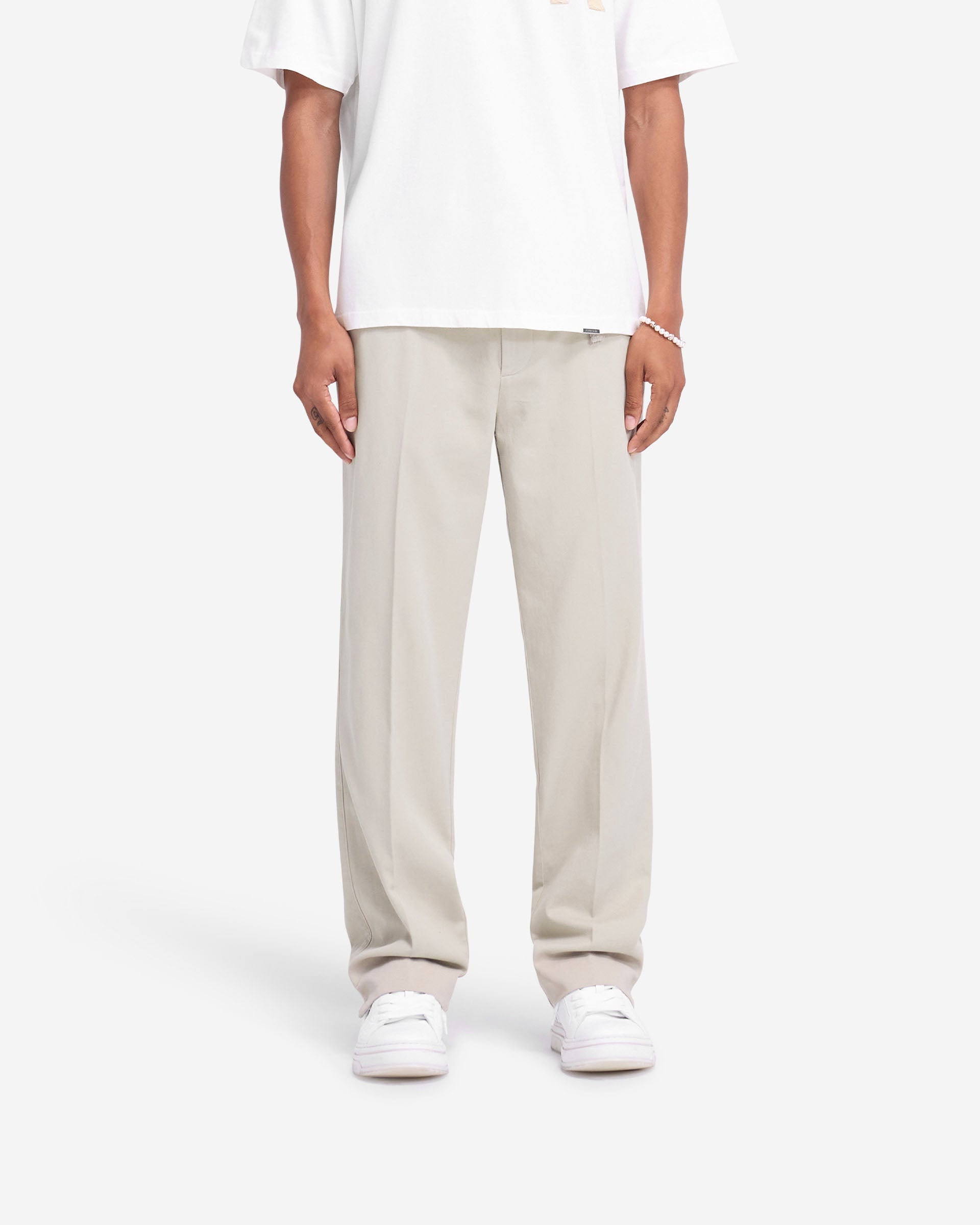 Man wearing stone cotton pants on a plain white background | Cotton Pant in Stone | Straight leg cotton pants with twin needle rise and pockets | FW24 Pants | Represent Clo
