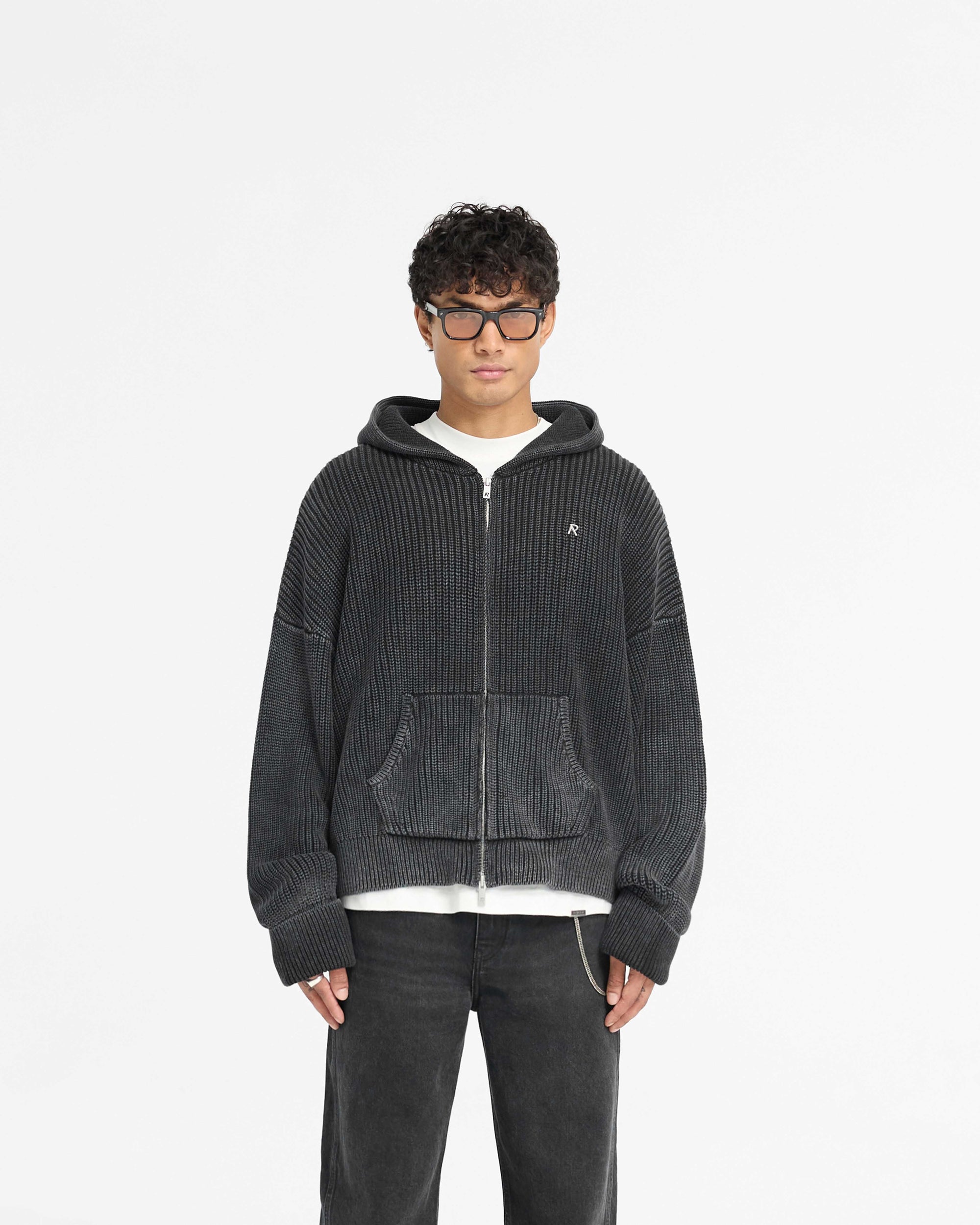 Man wearing a black ribbed hoodie on a plain white background | Ribbed Zip Through Hoodie in Jet Black | Oversized boxy fit hoodie with double zip closure | PRE SS25 Knitwear | Represent Clo