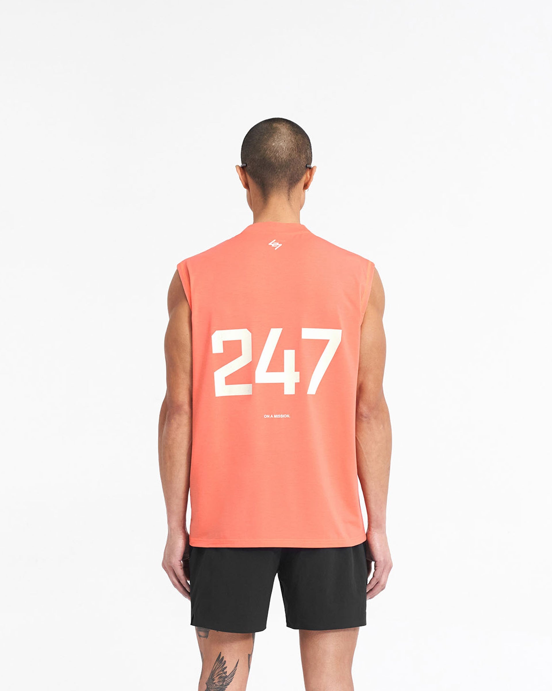 Man wearing an oversized coral tank top on a plain white background | 247 Oversized Tank in Coral | Lightweight breathable tank with 4-way stretch | 247 T-Shirts | Represent Clo