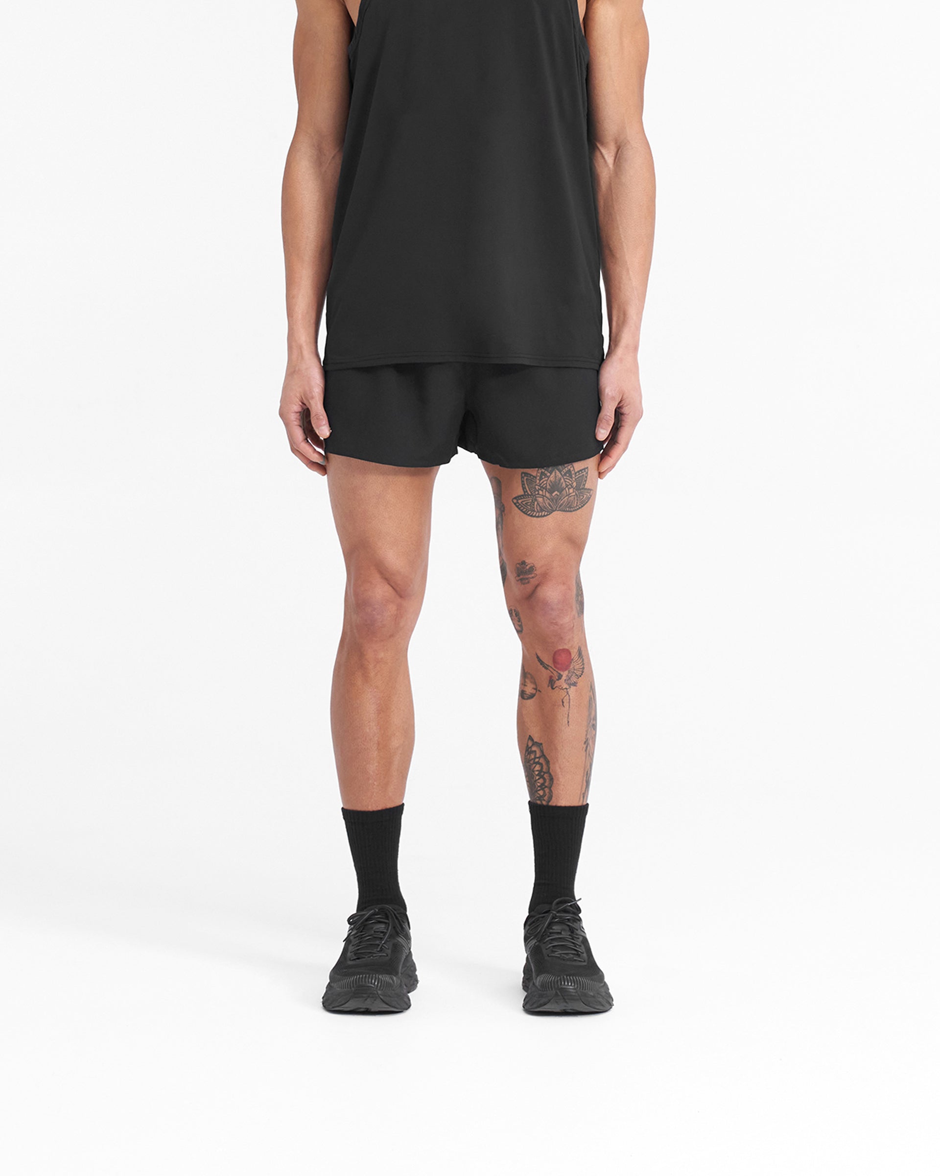 Man wearing black shorts with white details on a plain white background | Team 247 Race Shorts in Jet Black | Polyester shorts with large side splits and zip pocket | 247 Shorts | Represent Clo