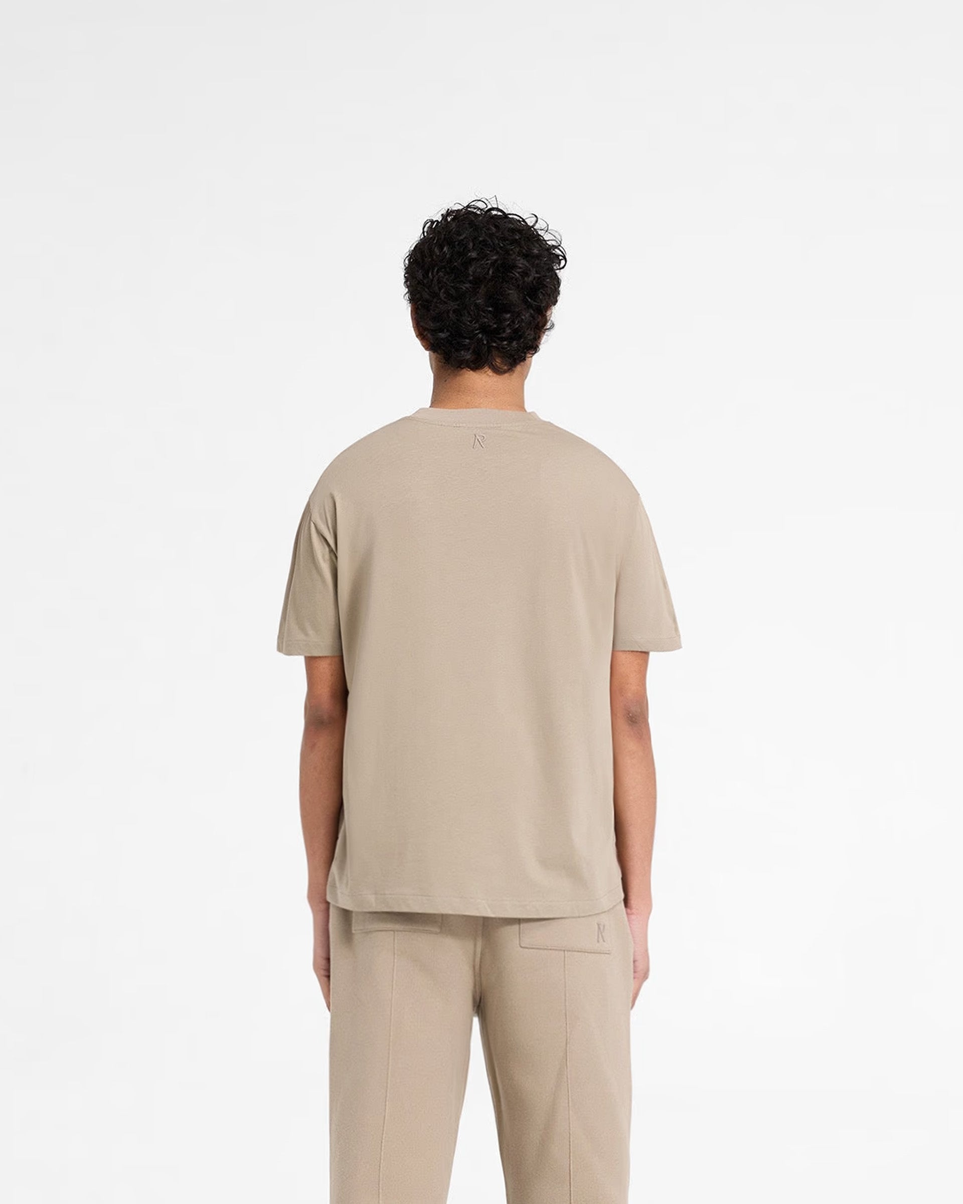 Man wearing a dune t-shirt on a plain white background | Initial T-Shirt in Dune | Slim fit mens t-shirt with embroidered details | Initial T-Shirts | Represent Clo