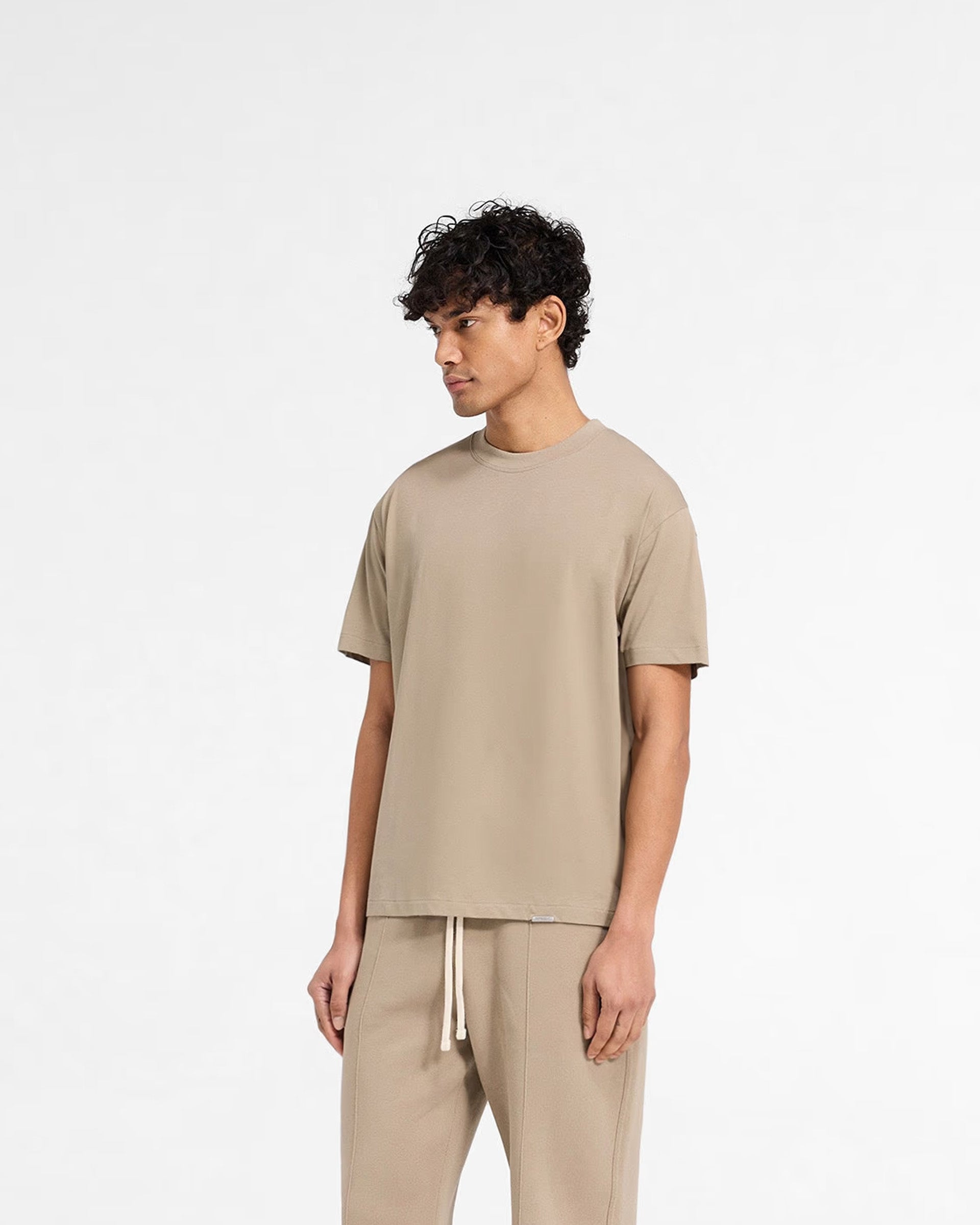 Back product image of a mens beige t-shirt on a plain white background | Initial T-Shirt in Dune | Regular fit t-shirt with embroidered back neck detail | Initial T-Shirts | Represent Clo