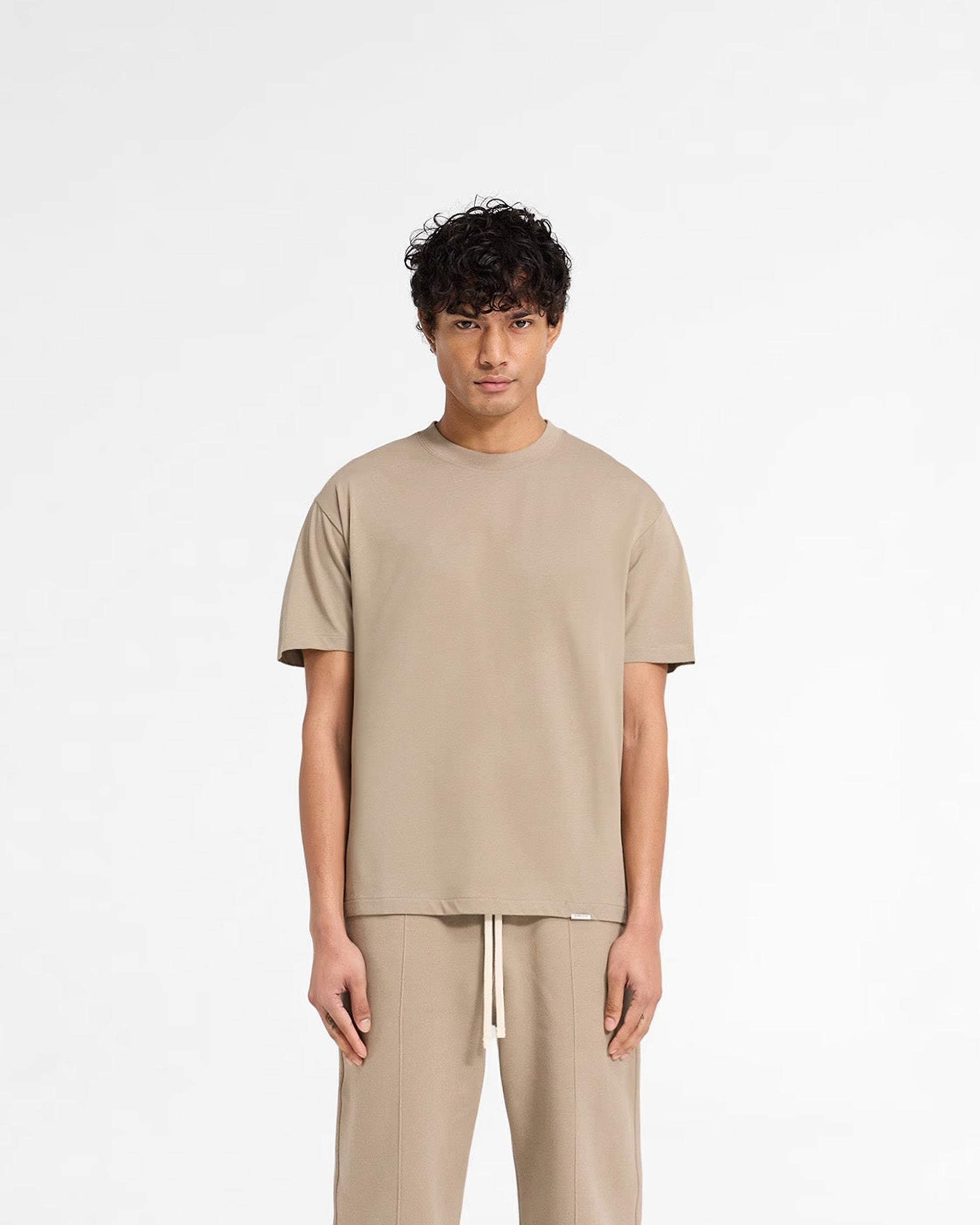 Man wearing a dune t-shirt on a plain white background | Initial T-Shirt in Dune | Fitted tee with embroidered back neck detail | Initial T-Shirts | Represent Clo