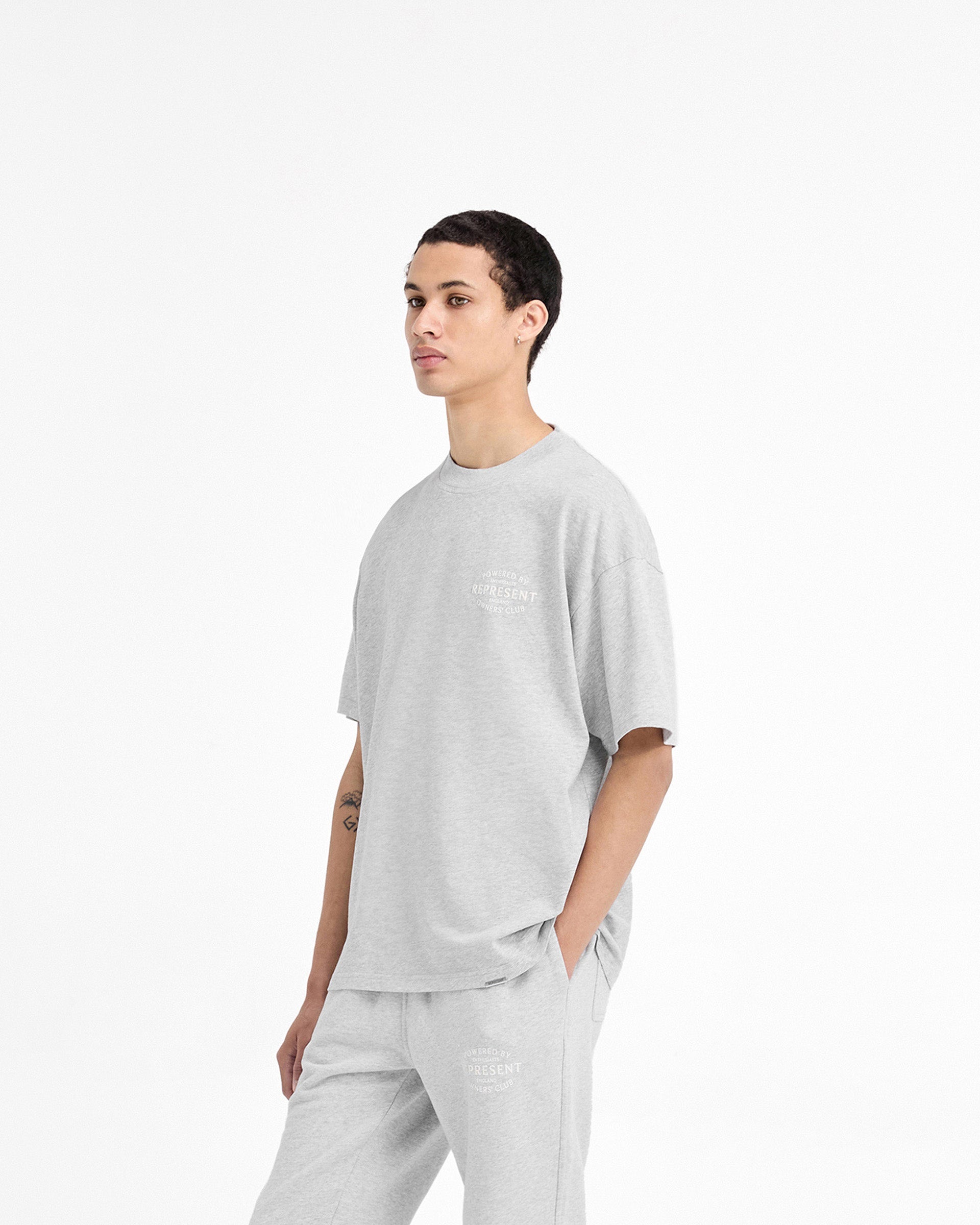 Man wearing an ash grey t-shirt on a plain white background | Represent Owners Club Stamp T-Shirt in Ash Grey | Medium weight slightly oversized t-shirt with high build branding | Owners Club T-Shirts | Represent Clo