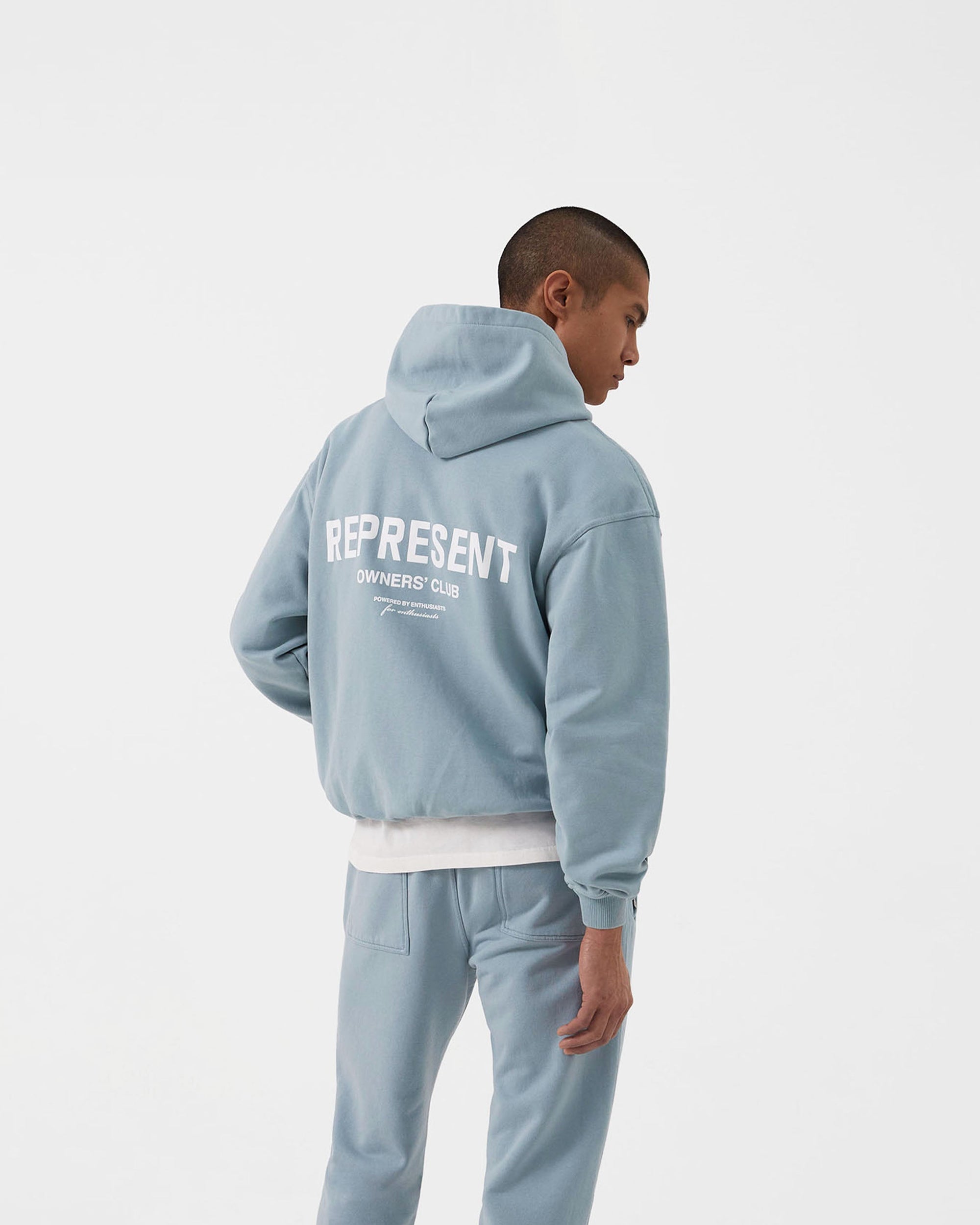 Man wearing an oversized blue hoodie on a plain white background | Represent Owners Club Hoodie in Powder Blue | Heavy weight jersey cotton hoodie with Owners Club print | Owners Club Hoodies | Represent Clo