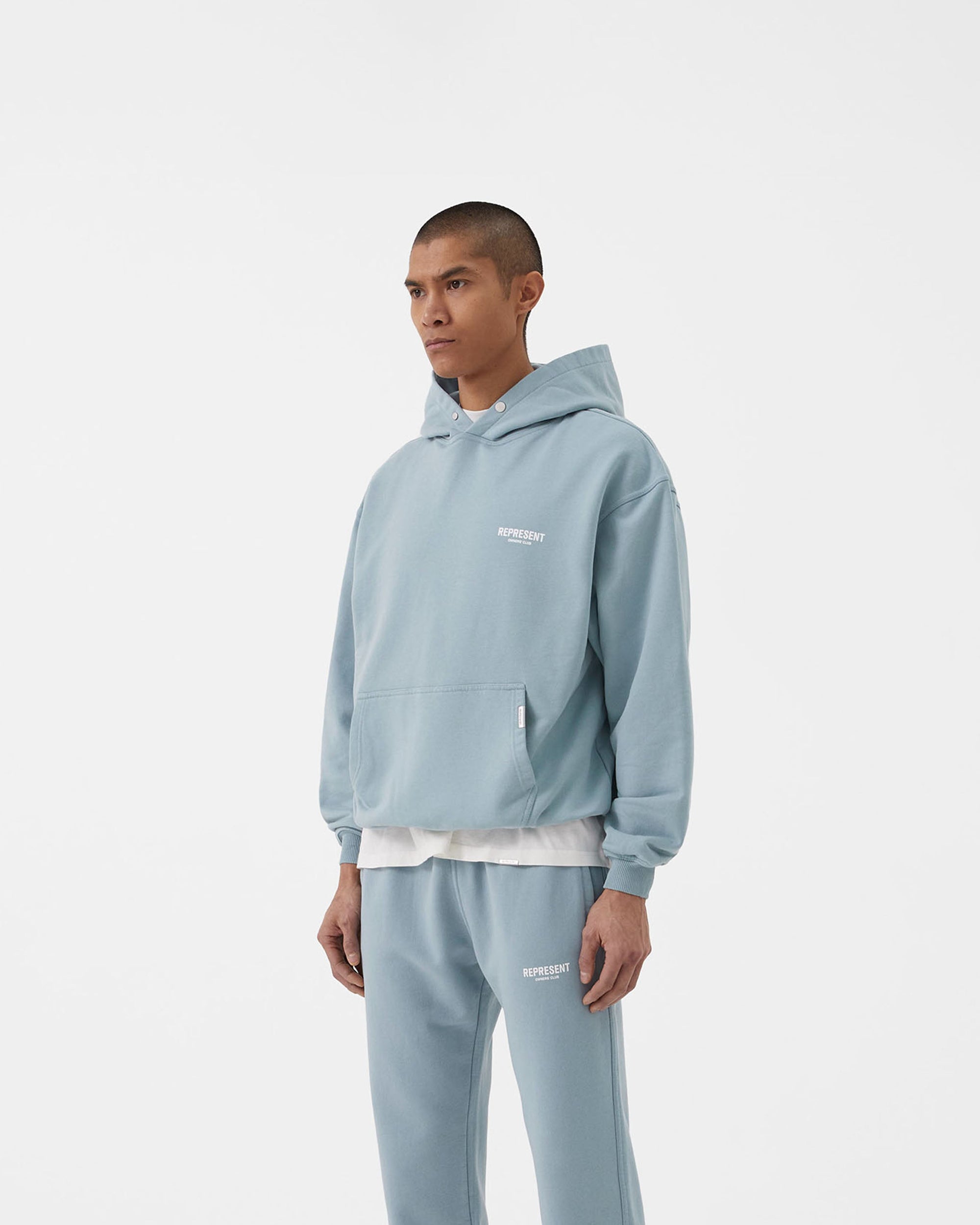 Man wearing a powder blue hoodie on a plain white background | Represent Owners Club Hoodie in Powder Blue | Oversized fit cotton hoodie with ribbed trims | Owners Club Hoodies | Represent Clo