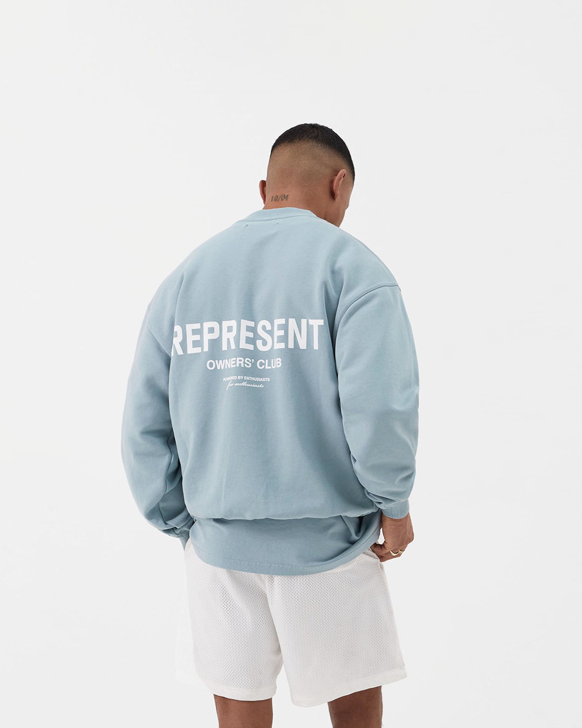 Man wearing a blue sweater on a plain white background | Represent Owners Club Sweater in Powder Blue | Oversized fit crewneck sweater with ribbed trims | Owners Club Sweaters | Represent Clo