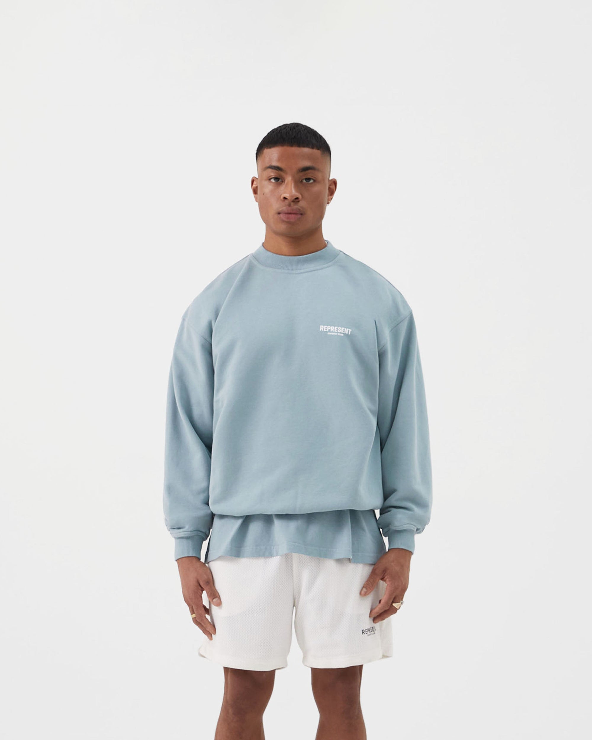 Man wearing an oversized blue sweater on a plain white background | Represent Owners Club Sweater in Powder Blue | Heavy weight jersey cotton crewneck sweater | Owners Club Sweaters | Represent Clo