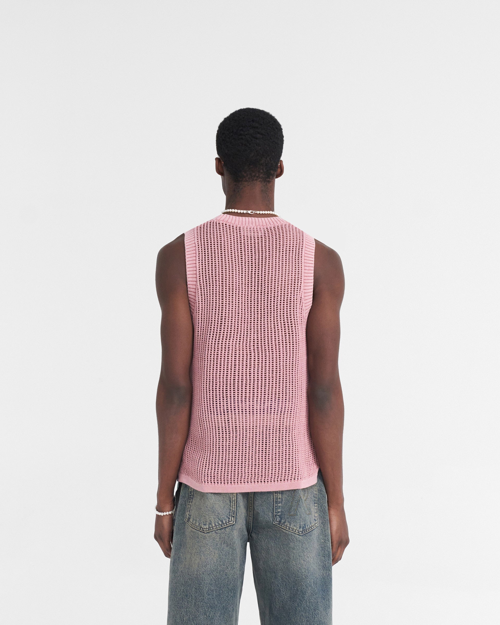 Man wearing an orange knit vest on a plain white background | Washed Knit Vest in Sunrise | Regular fit knitwear with ribbed neckline | SS24 Knitwear | Represent Clo