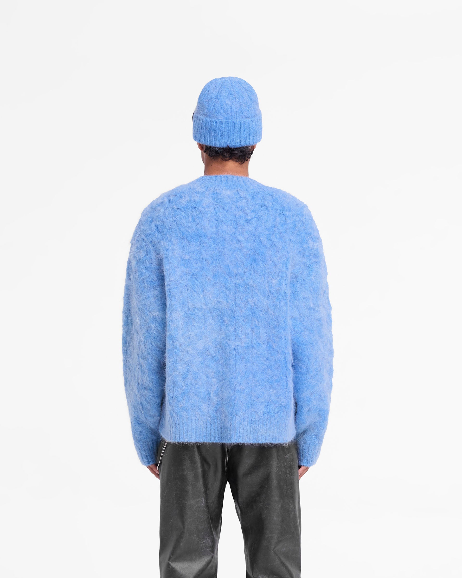 Man wearing an electric blue knit sweater on a plain white background | Cable Knit Sweater in Electric Blue | Very oversized mohair jumper with ribbed hem | FW24 Knitwear | Represent Clo