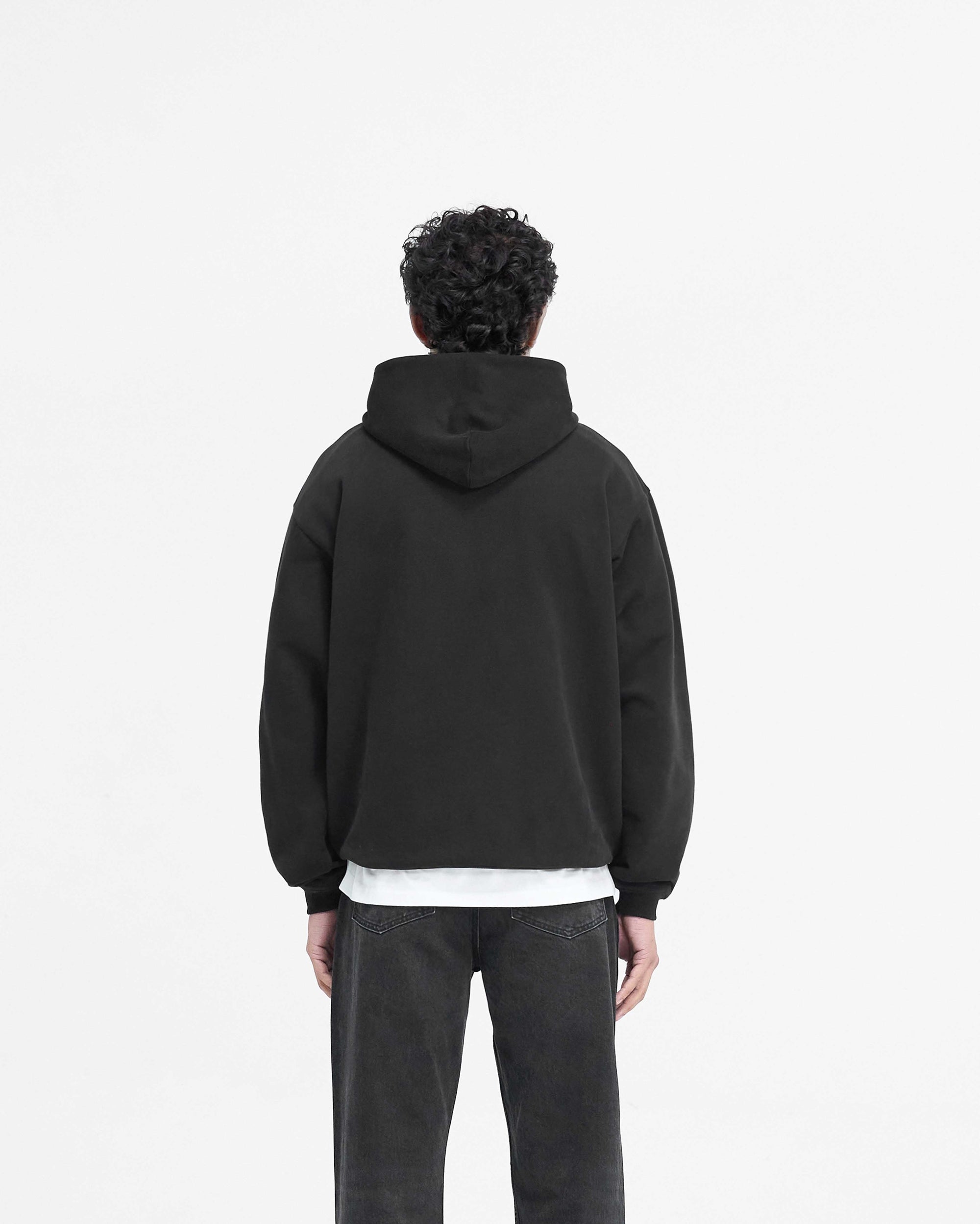 Man wearing a black hoodie on a plain white background | Script Logo Hoodie in Black | Slightly oversized hoodie with matte script embroidery | PRE SS25 Hoodies | Represent Clo
