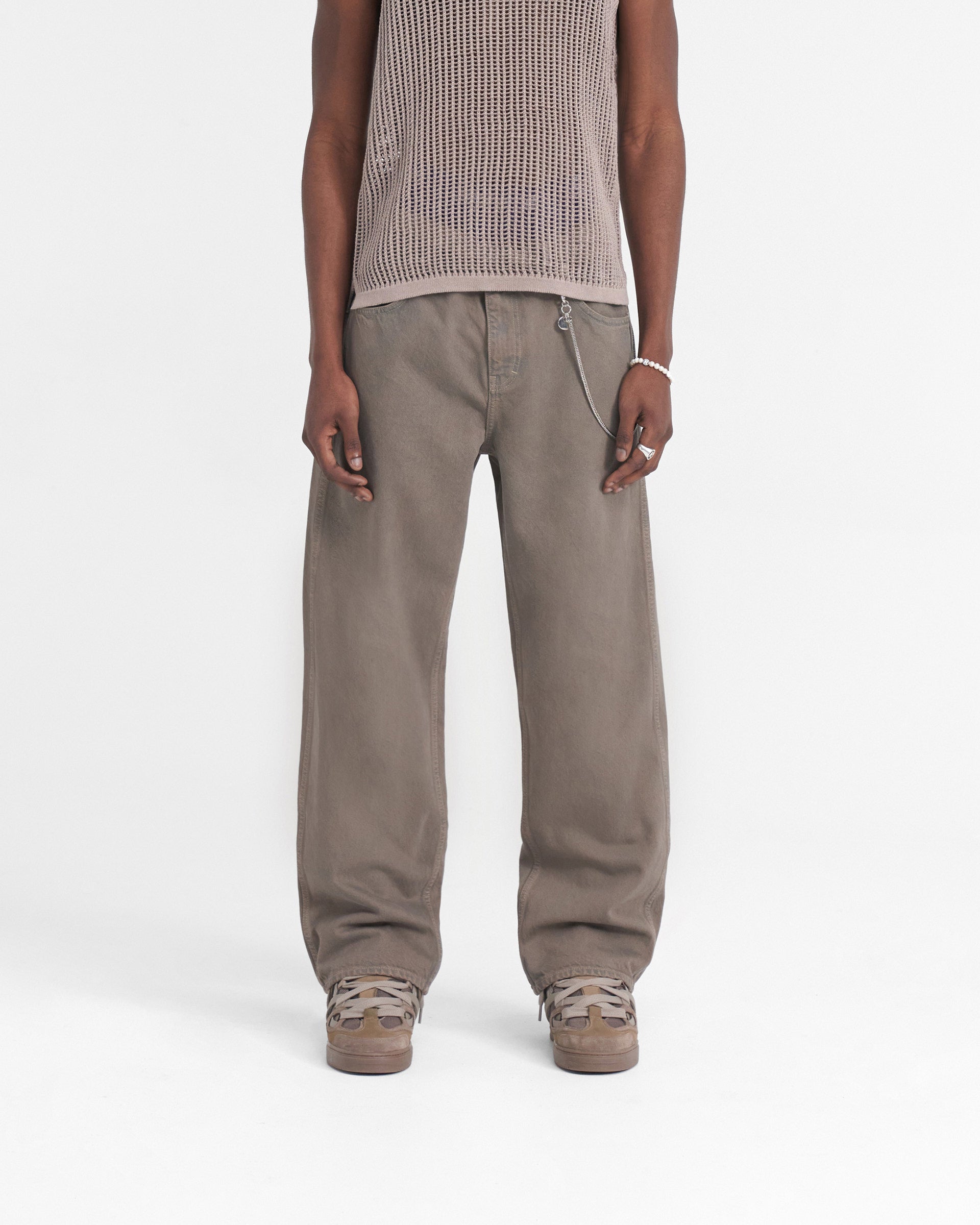 Man wearing a baggy denim jeans in grey on a plain white background | R3 Baggy Denim in Rock | Baggy fit jeans with branded metal trims | SS24 Denim | Represent Clo