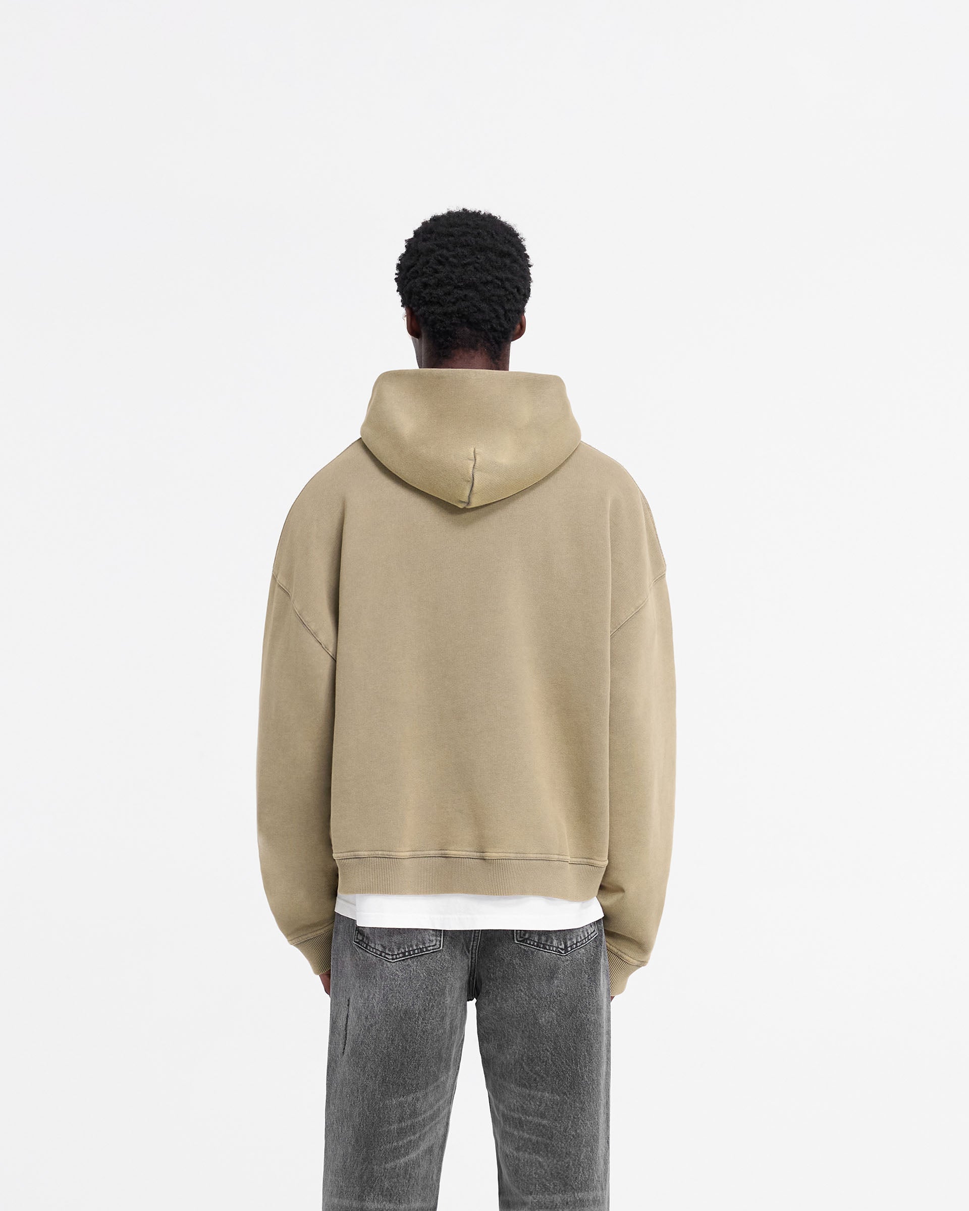 Man wearing an oversized brown hoodie on a plain white background | Rep Applique Hoodie in Fawn | Boxy fit hoodie with applique logo and ribbed details | FW24 Hoodies | Represent Clo
