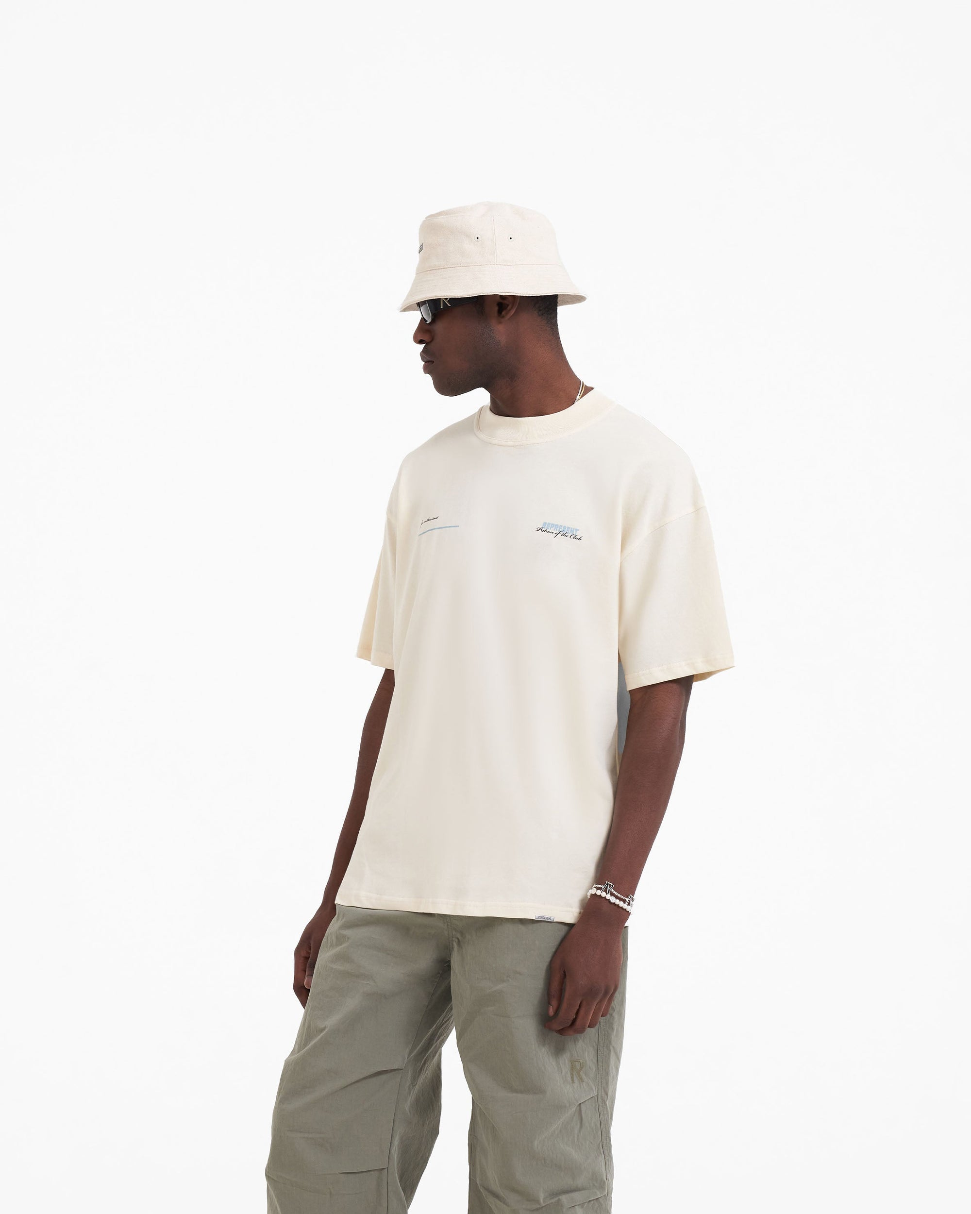 Back product image of a mens cream t-shirt on a plain white background | Patron Of The Club T-Shirt in Buttercream Powder Blue | Oversized fit t-shirt with screen printed branding | Patrons T-Shirts | Represent Clo