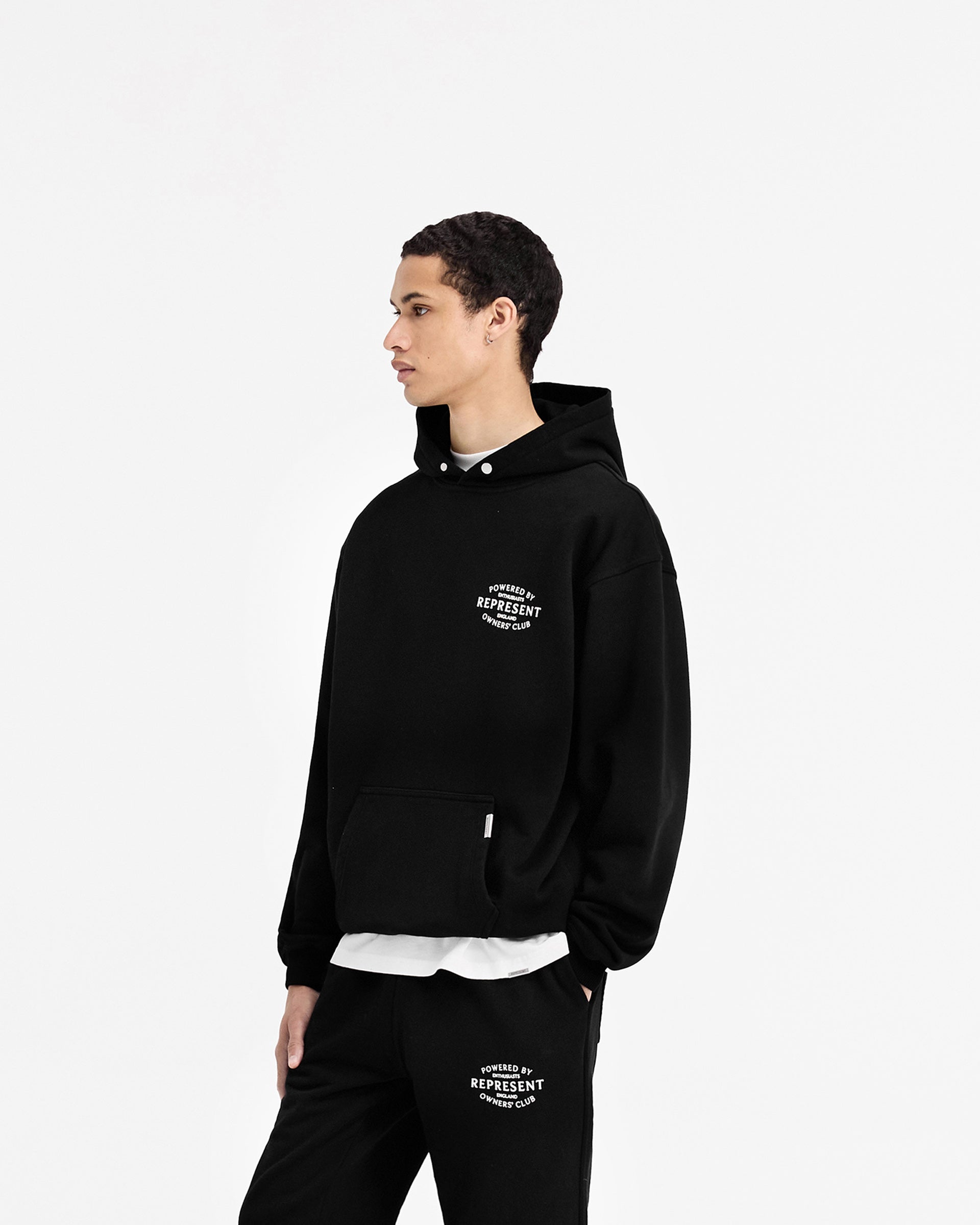 Man wearing a black hoodie on a plain white background | Represent Owners Club Stamp Hoodie in Jet Black | Hoodie with high build branding and ribbed hem | Owners Club Hoodies | Represent Clo
