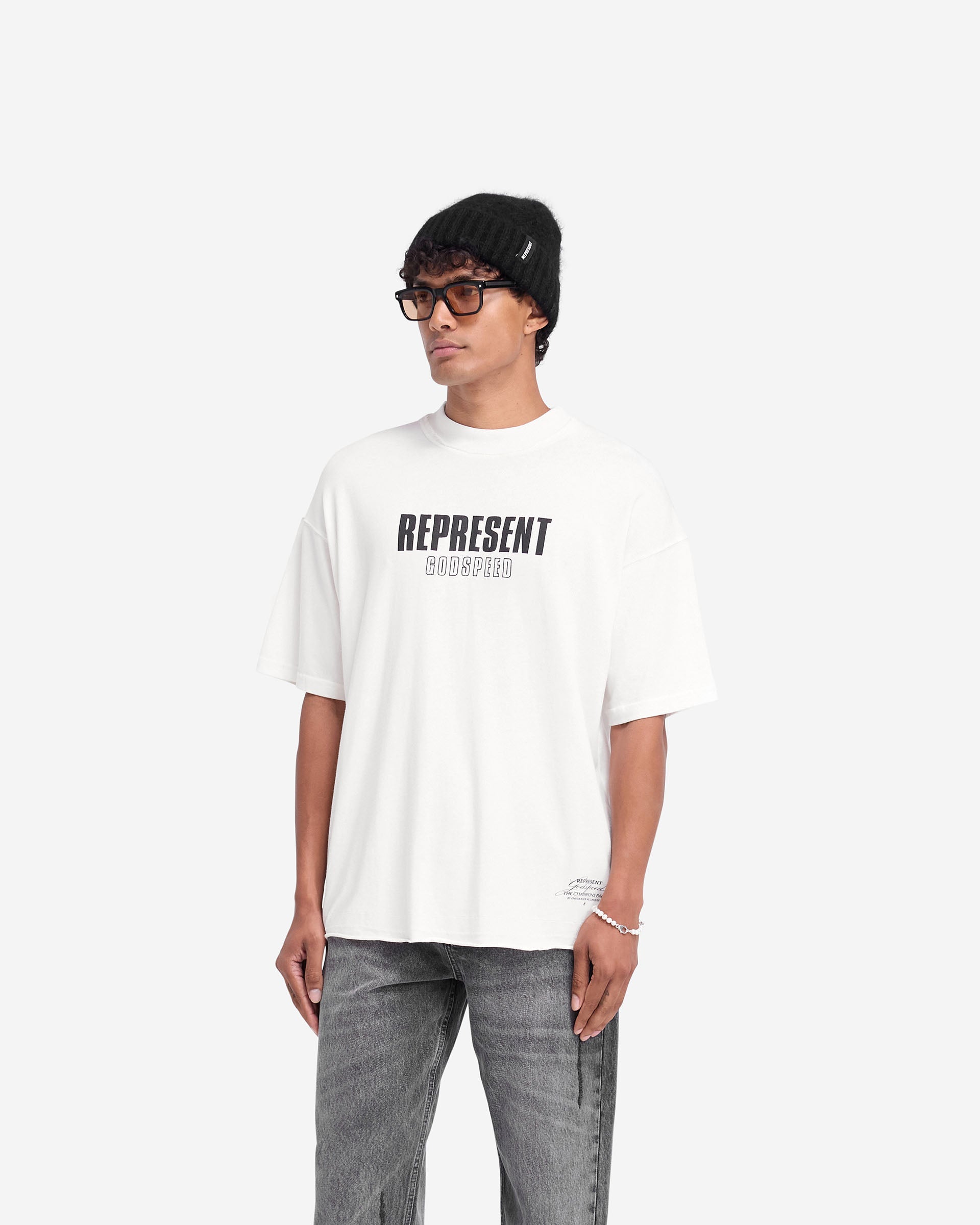 Man wearing a white t-shirt on a plain white background | Godspeed T-Shirt in Flat White | Oversized t-shirt with raw hem and cracked graphics | FW24 T-Shirts | Represent Clo