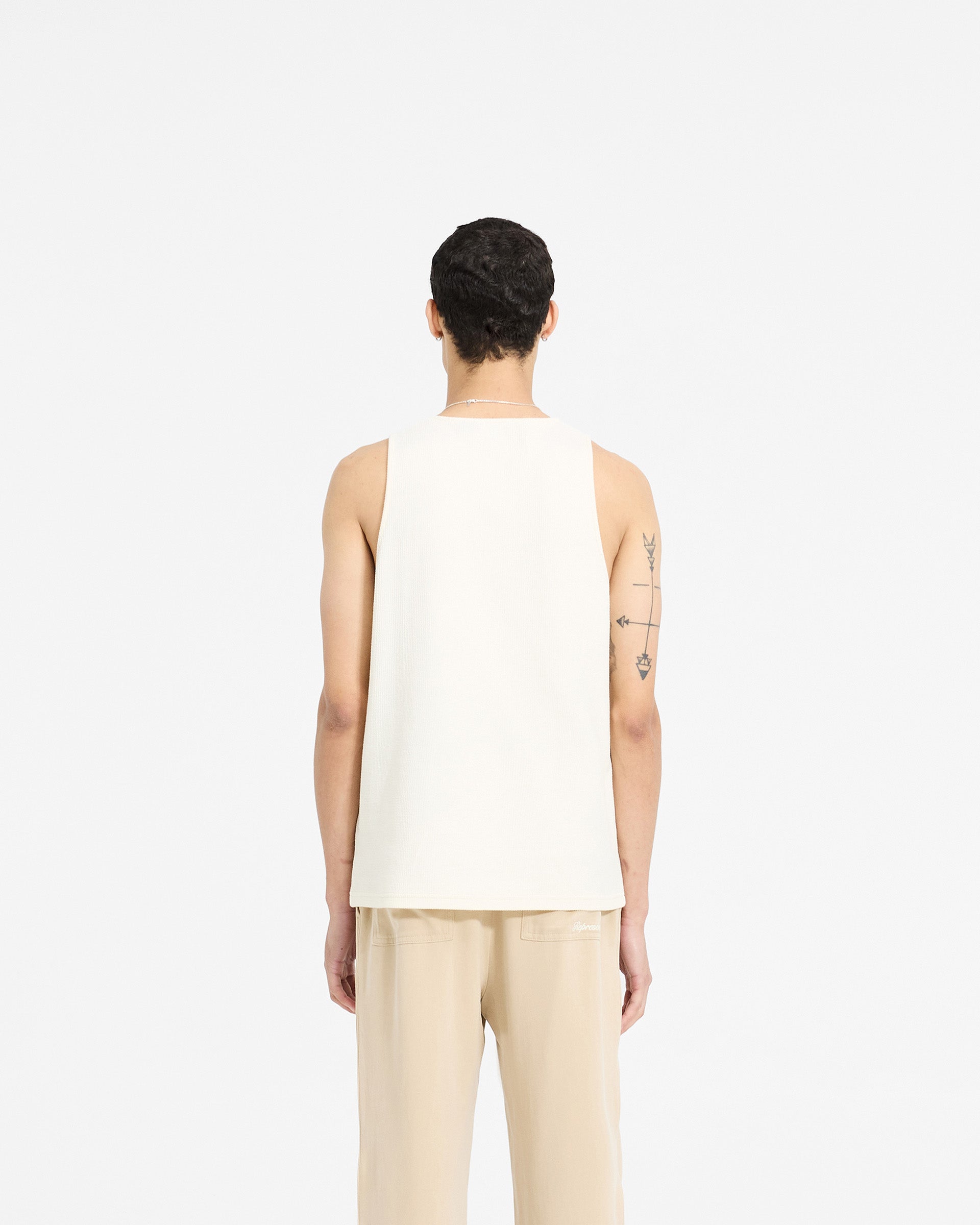 Man wearing a white vest on a plain white background | Waffle Vest in Antique White | Regular fit vest with Represent embroidery | SC24 T-Shirts | Represent Clo