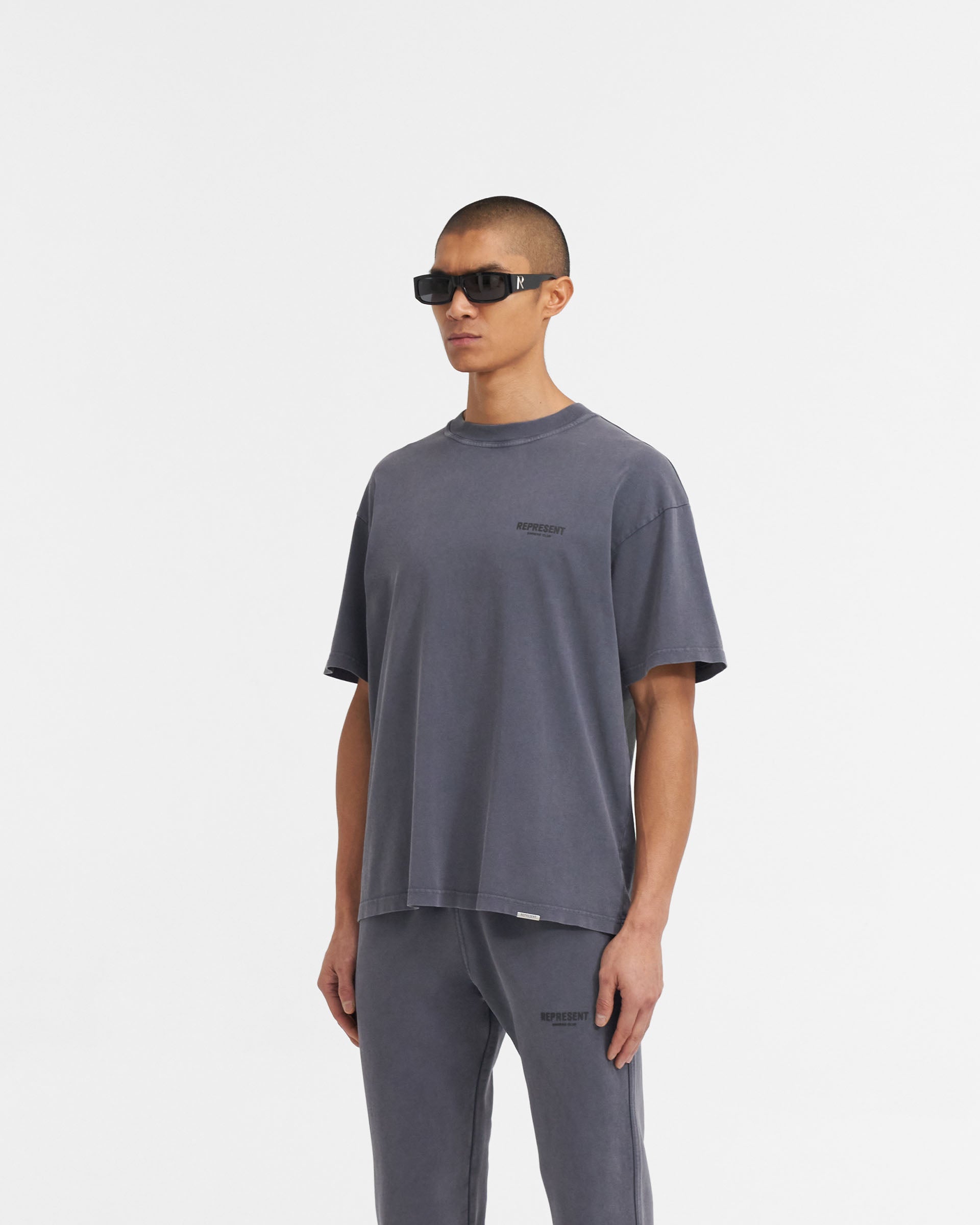 Man wearing a grey t-shirt on a plain white background | Represent Owners Club T-Shirt in Storm | Short sleeve cotton t-shirt with ribbed crewneck | Owners Club T-Shirts | Represent Clo