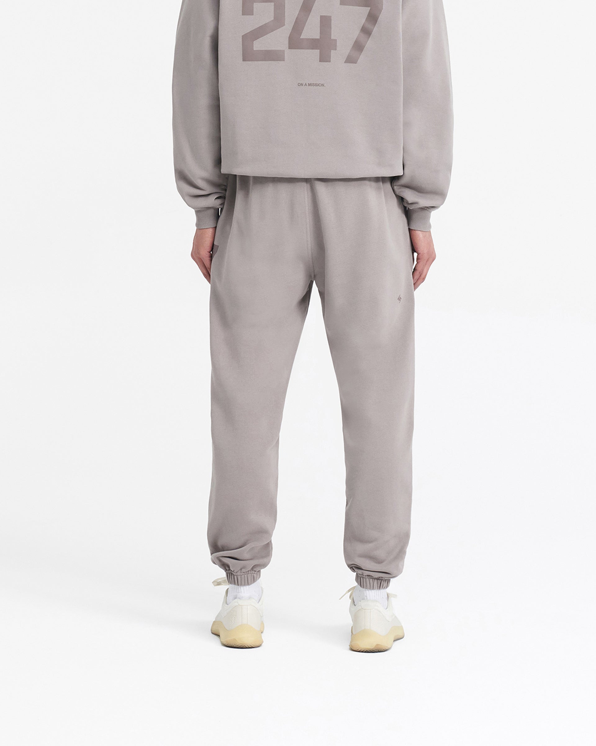 Man wearing grey sweatpants on a plain white background | 247 Sweatpant in Cinder | Training joggers with elasticated cuffs and internal drawcord | 247 Pants | Represent Clo