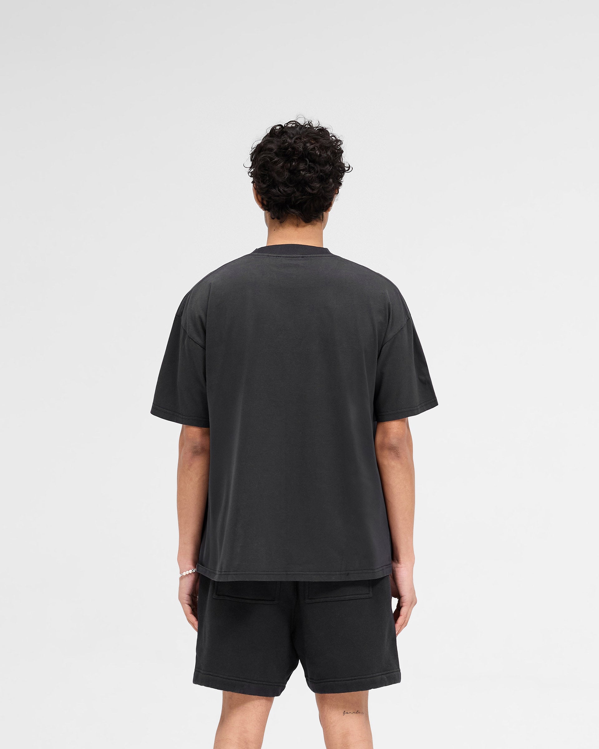 Man wearing a black t-shirt on a plain white background | Rep Applique T-Shirt in Off Black | Slightly oversized t-shirt with textured applique | SS25 T-Shirts | Represent Clo