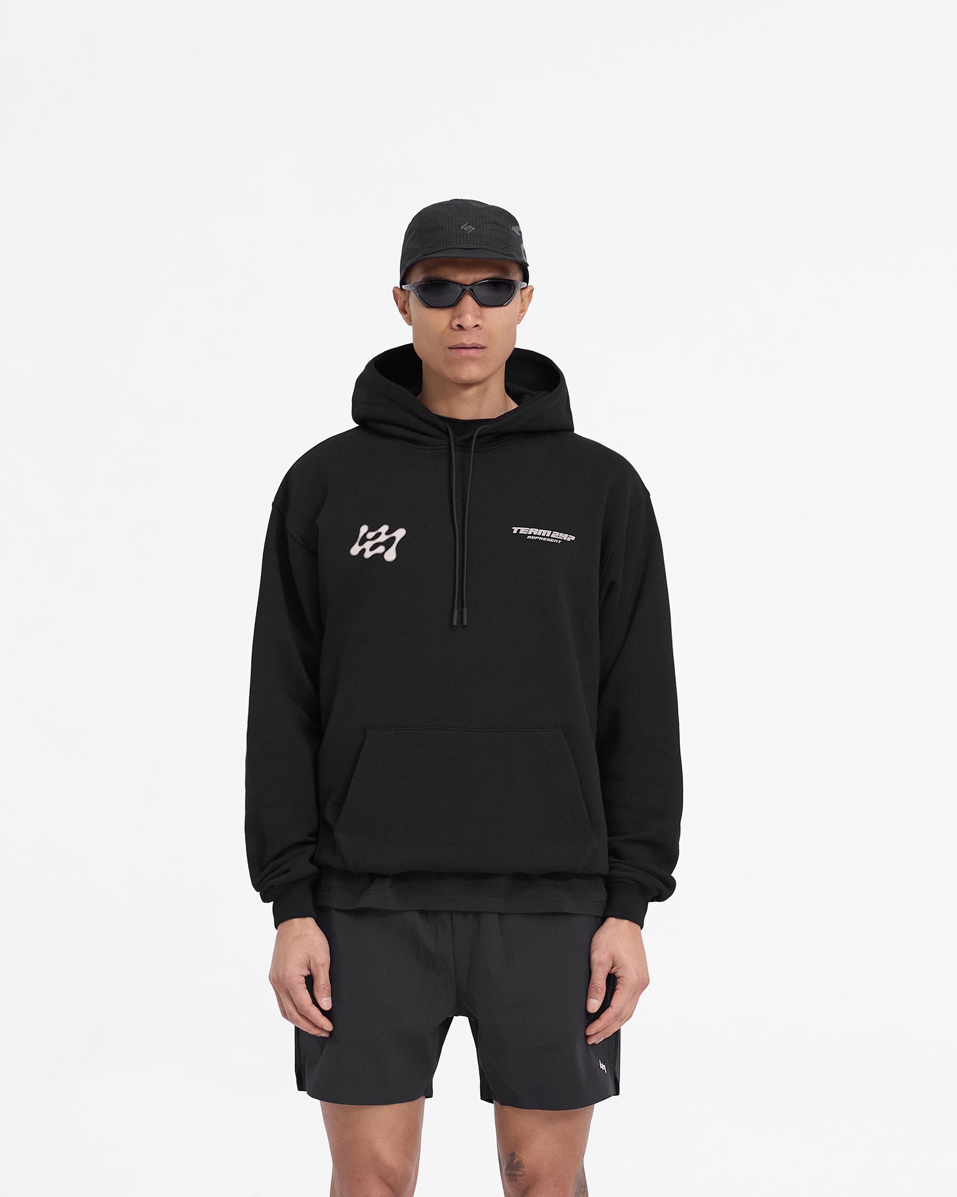 Man wearing an oversized black hoodie on a plain white background | 247 Future Terrains Oversized Hoodie in Black | Heavyweight training hoodie with Team 247 branding | 247 Hoodies | Represent Clo