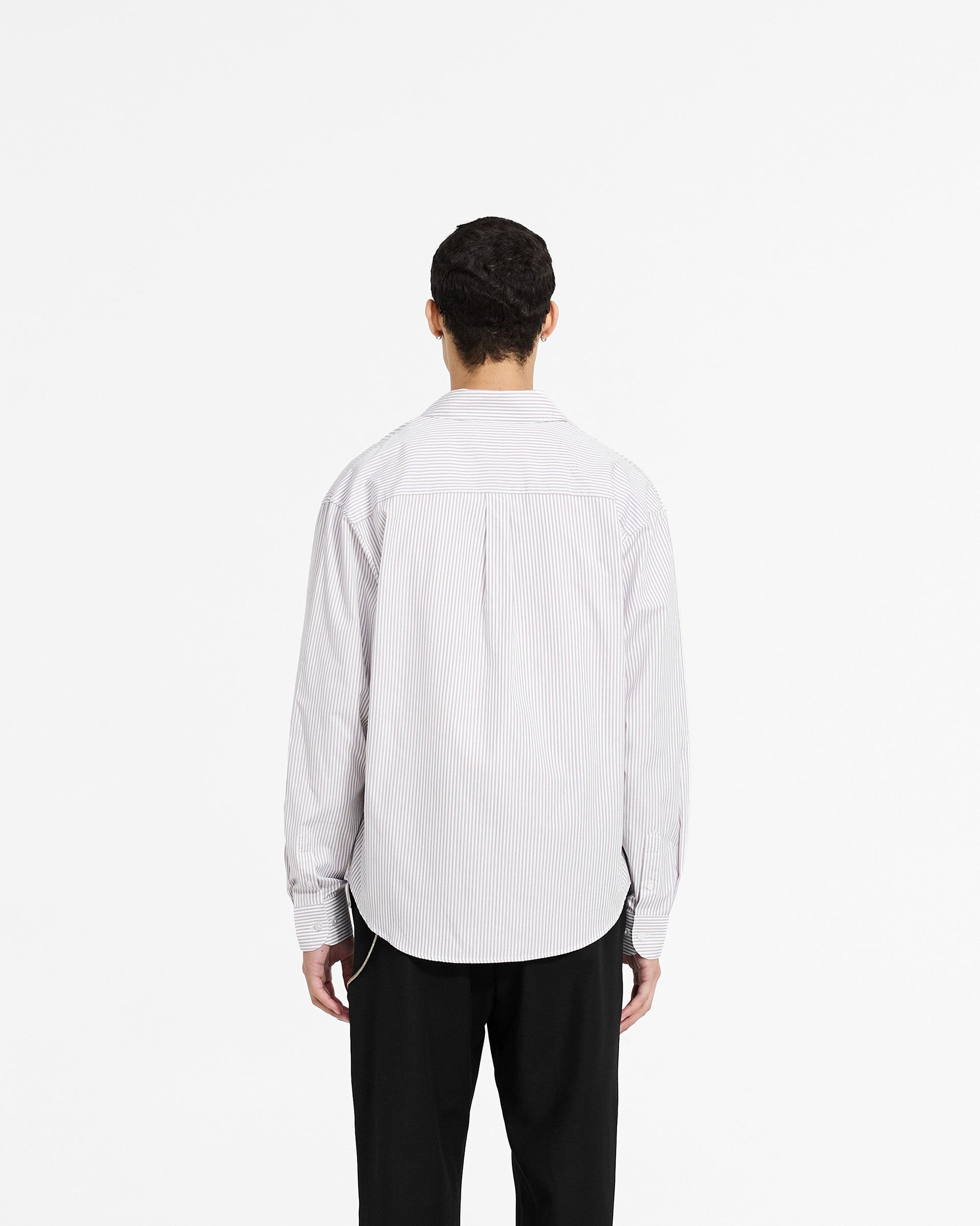 Man wearing a grey pinstripe shirt on a plain white background | Long Sleeve Pinstripe Shirt in Grey | Slightly oversized fit with curved hem | SC24 Shirts | Represent Clo