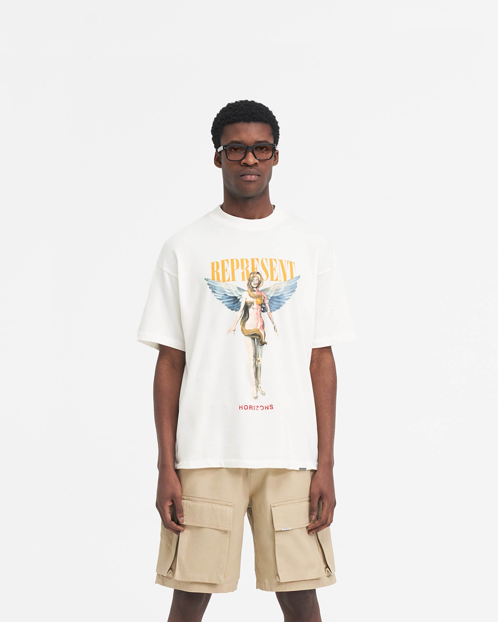 Man wearing an oversized white t-shirt with graphic print on a plain white background | Reborn T-Shirt in Flat White | Oversized graphic t-shirt in medium weight cotton | SS24 T-Shirts | Represent Clo