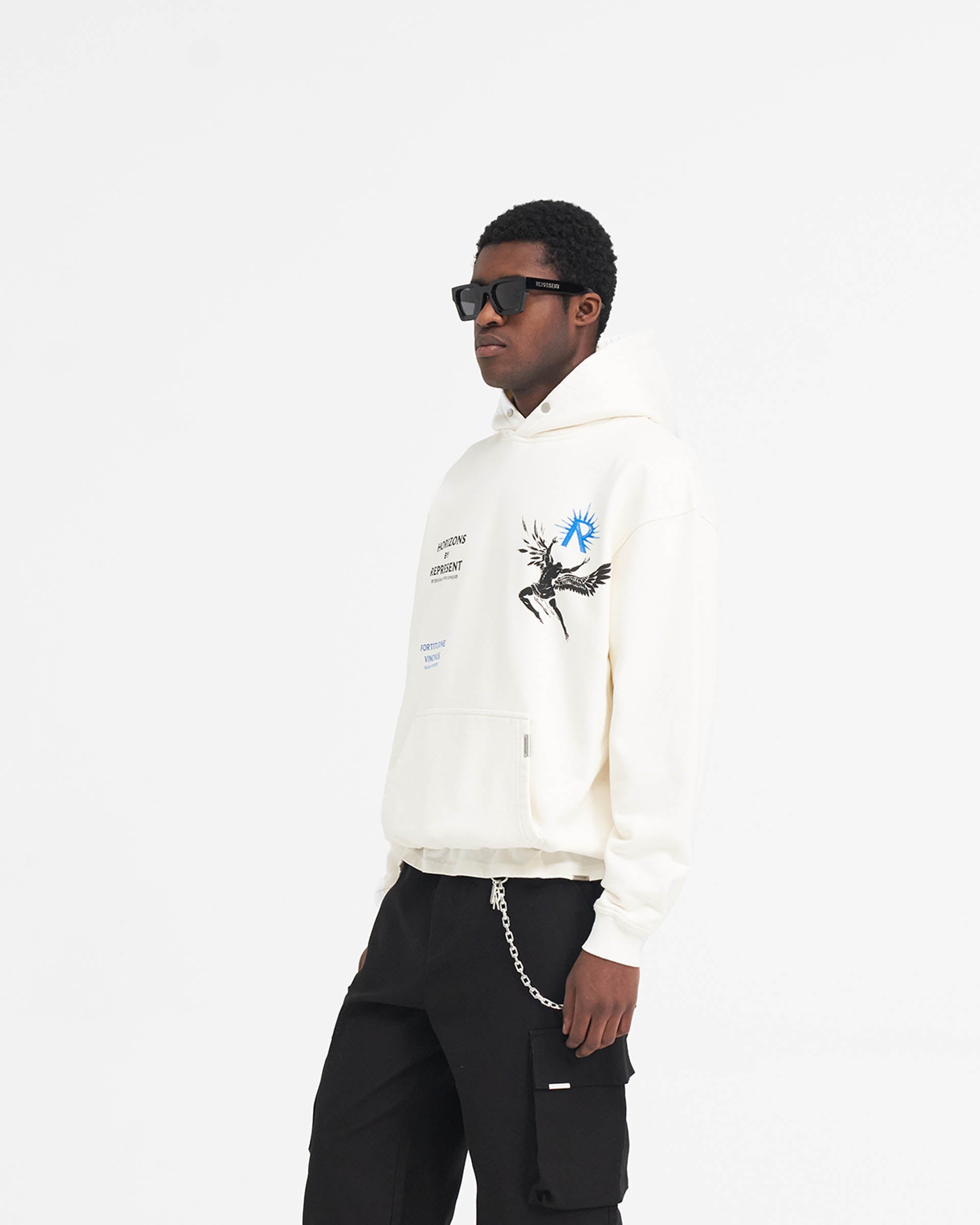 Man wearing an oversized white hoodie on a plain white background | Icarus Hoodie in Flat White | Luxury hoodie with Icarus graphic and Cobrax popper | SS24 Hoodies | Represent Clo