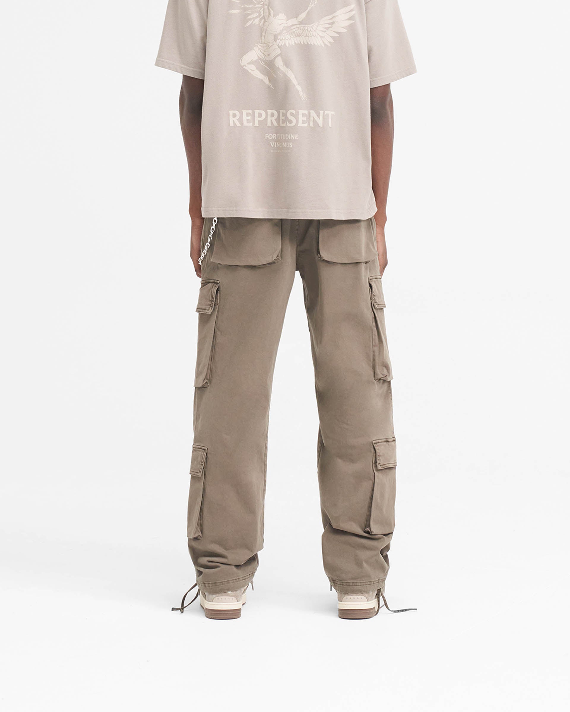 Man wearing baggy blue cargo pants on a plain white background | Baggy Cargo Pant in Dawn | Cargo pants with 3D oversized pockets and spray dye effect | SS24 Pants | Represent Clo