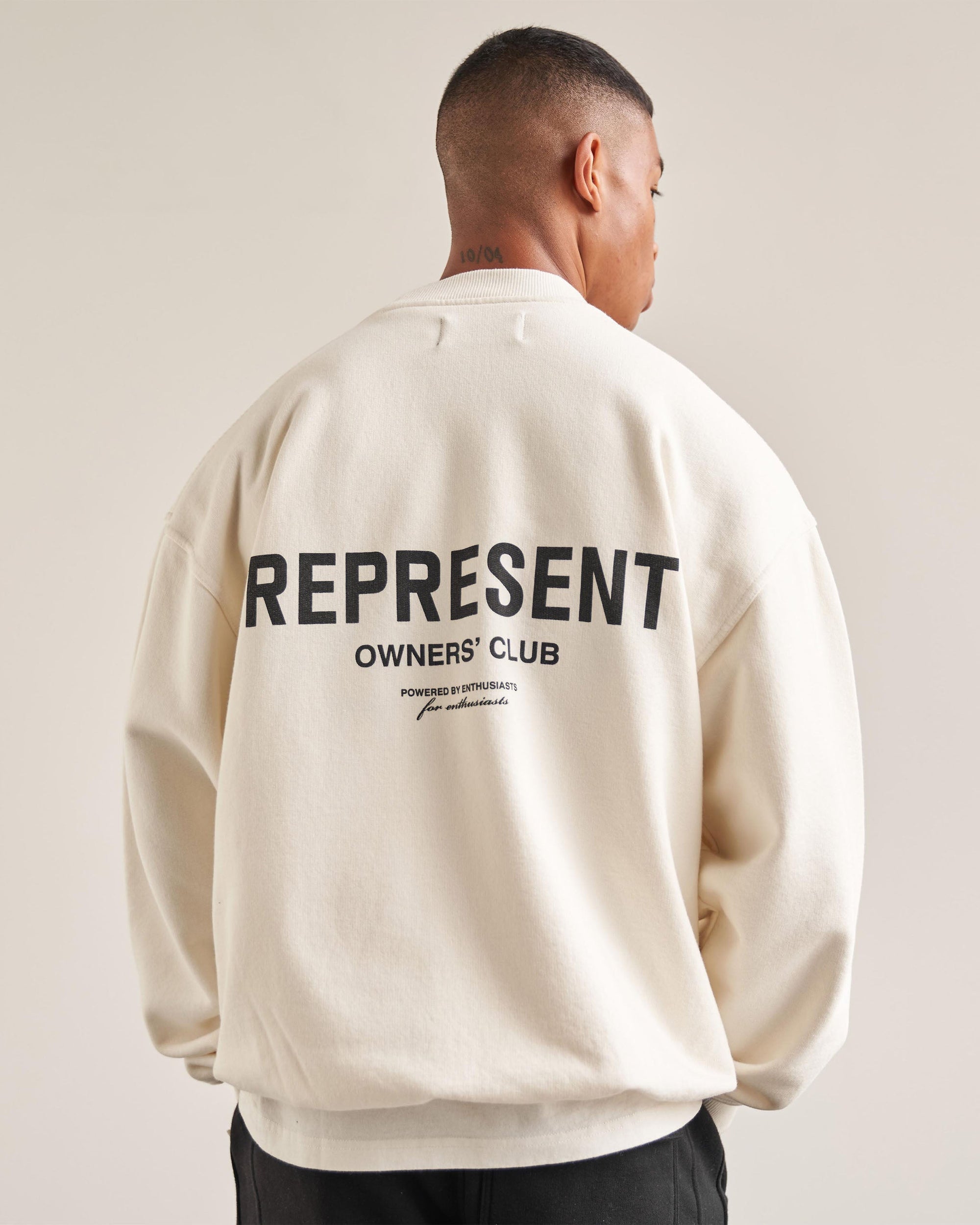 Man wearing a white sweater on a plain white background | Represent Owners Club Sweater in Flat White | Oversized fit heavyweight crewneck sweater | Owners Club Sweaters | Represent Clo