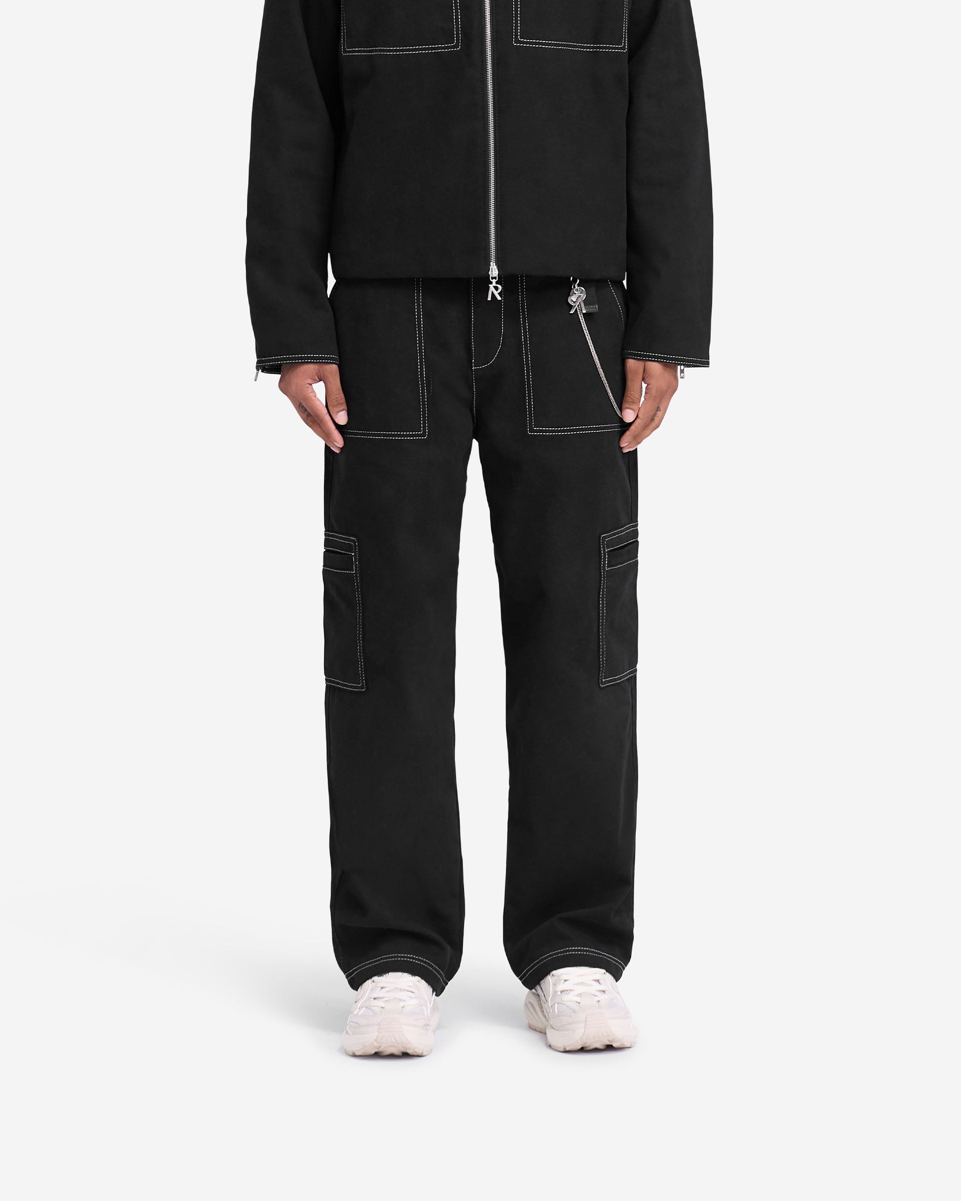 Man wearing a black pant with contrast stitching on a plain white background | Contrast Stitch Pant in Jet Black | Relaxed straight leg pants with cargo pockets | FW24 Pants | Represent Clo