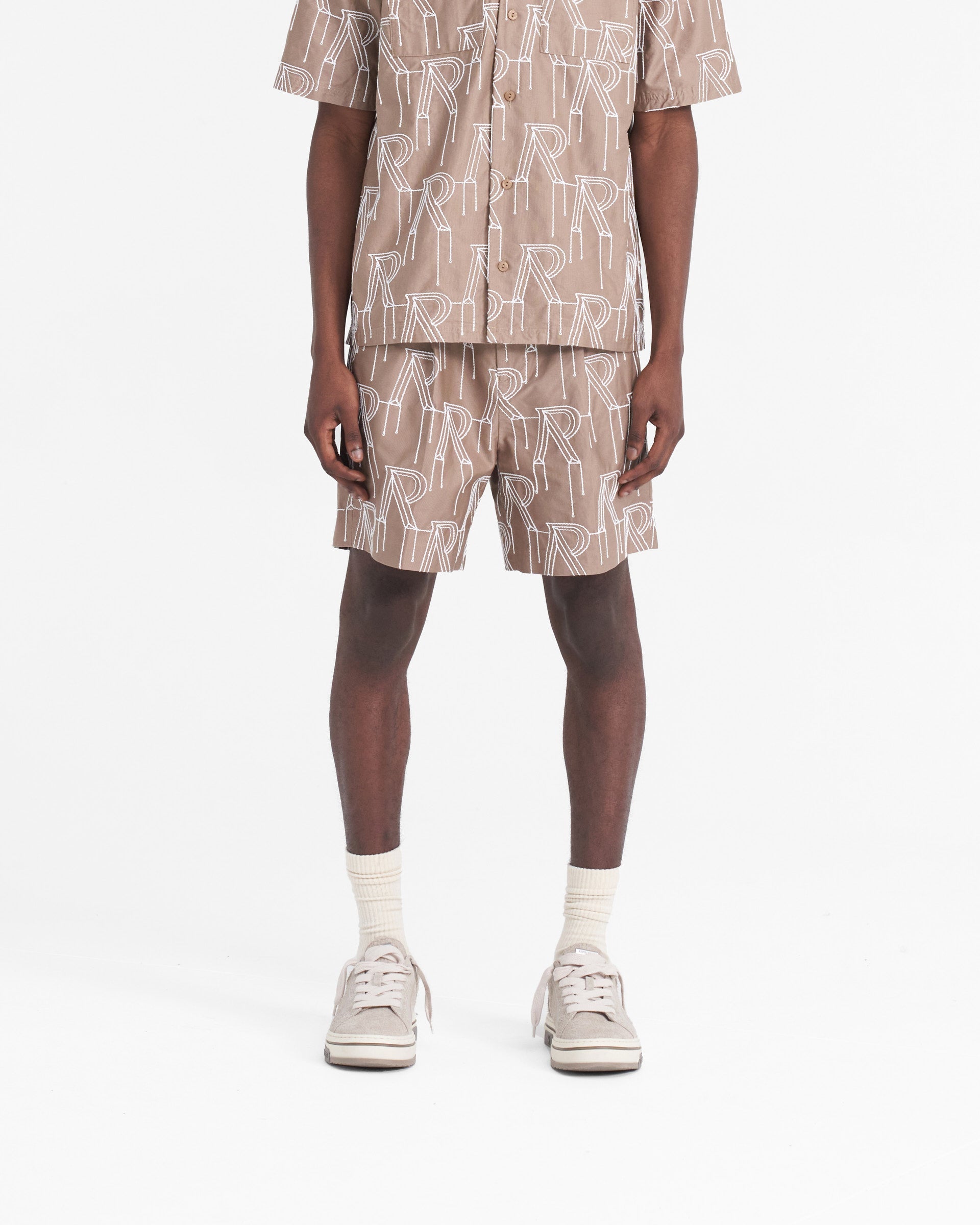 Man wearing washed taupe shorts on a plain white background | Embroidered Initial Tailored Short in Washed Taupe | Tailored shorts with raised chain stitch embroidery | SS24 Shorts | Represent Clo