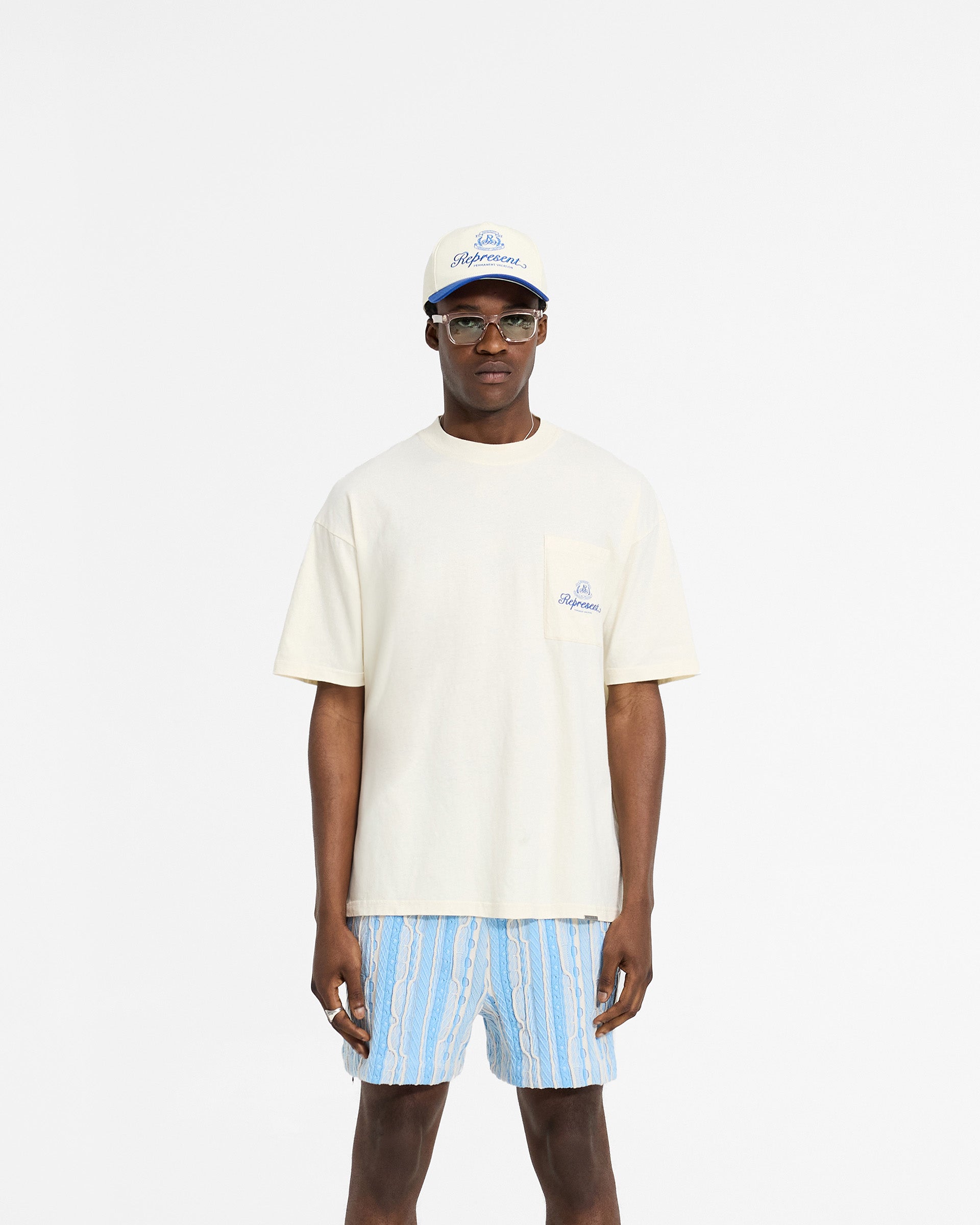 Man wearing an antique white t-shirt on a plain white background | Permanent Vacation Pocket T-Shirt in Antique White | Oversized t-shirt with pocket and artwork | SC24 T-Shirts | Represent Clo