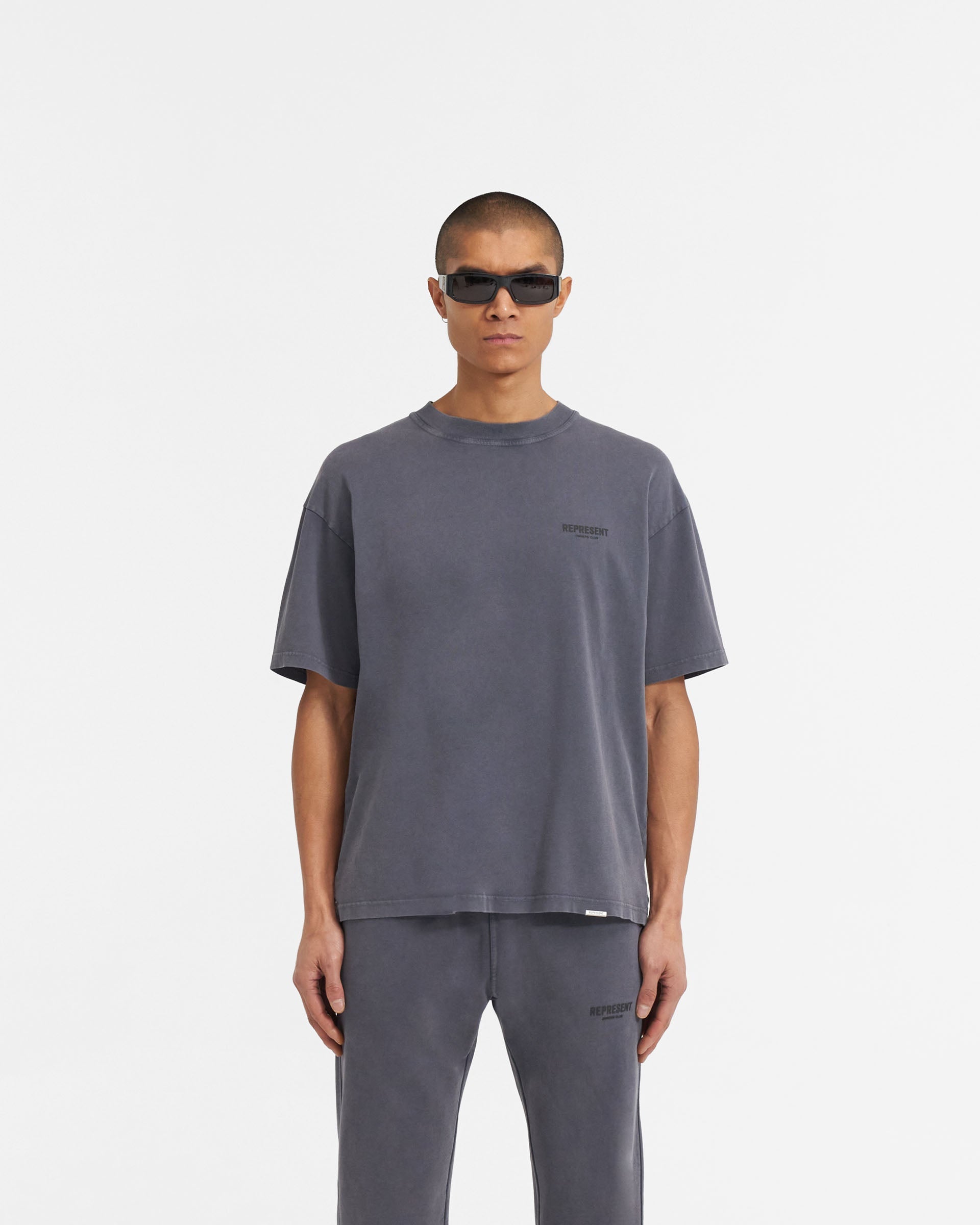 Man wearing a grey t-shirt on a plain white background | Represent Owners Club T-Shirt in Storm | Short sleeve cotton t-shirt with high build branding | Owners Club T-Shirts | Represent Clo