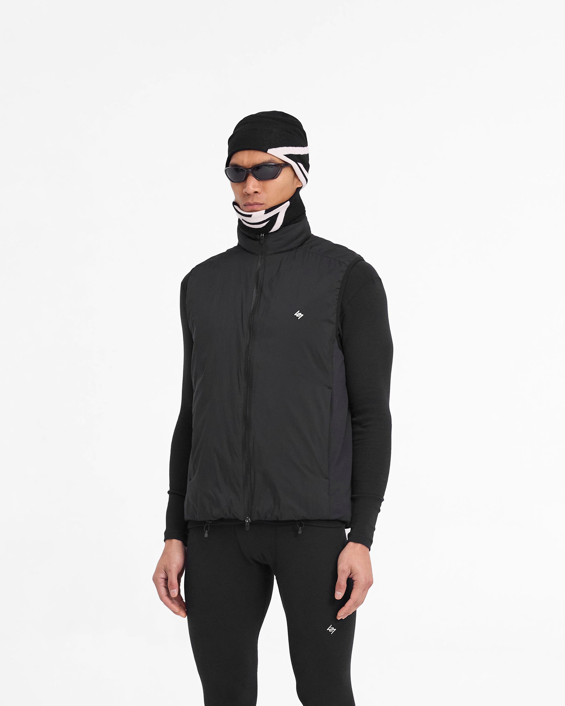 Man wearing a black insulated gilet on a plain white background | Team 247 Insulated Gilet in Black | Gilet with gridded fleece side seam panelling and double ended zip closure | 247 Outerwear | Represent Clo