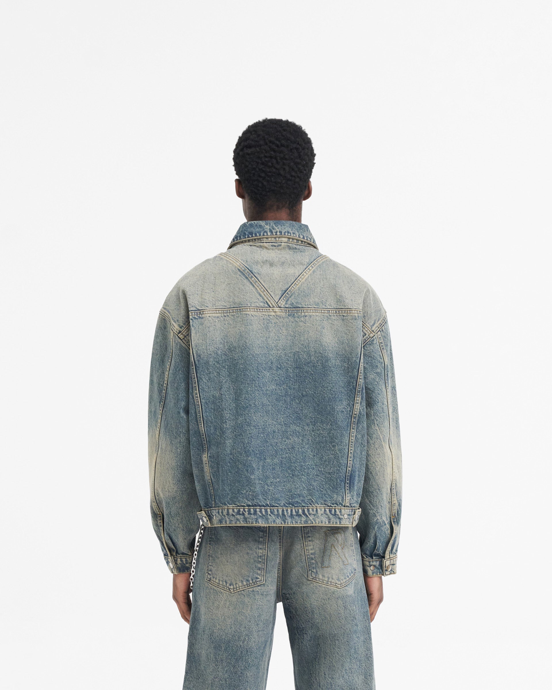 Man wearing a blue denim jacket on a plain white background | R4 Denim Jacket in Blue Cream | Oversized denim jacket with RiRi zip and chest flap pockets | SS24 Denim | Represent Clo